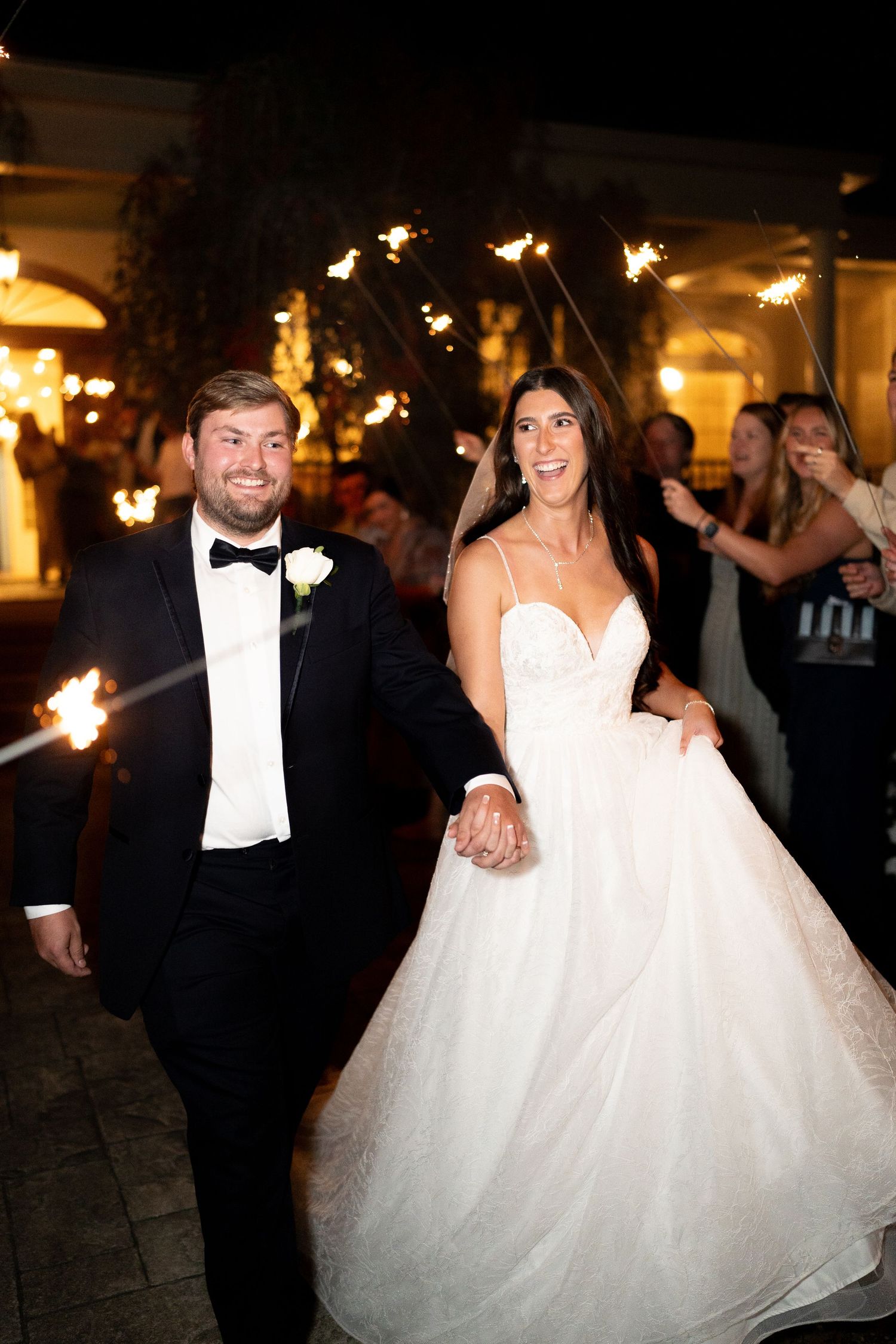 Newlyweds dancing together at night with sparklers creating a magical atmosphere.
