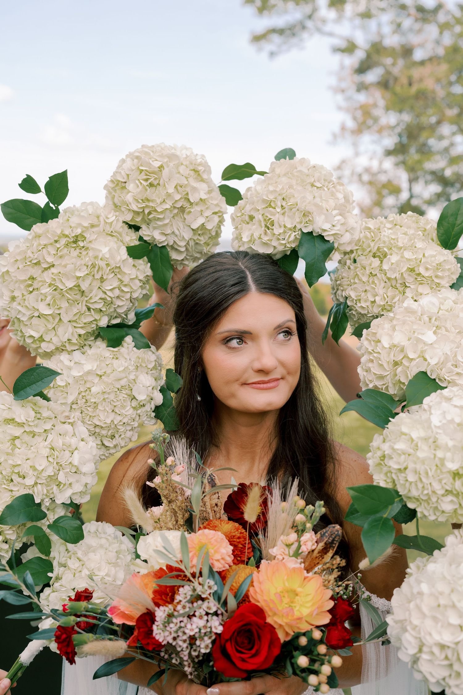 Bridal party posing with lush white hydrangea bouquets and fall-colored floral arrangements.