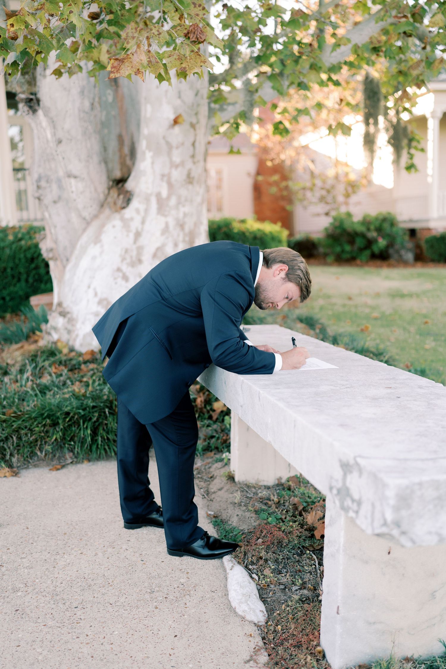 Wedding document being signed at a white table outdoors during the ceremony.