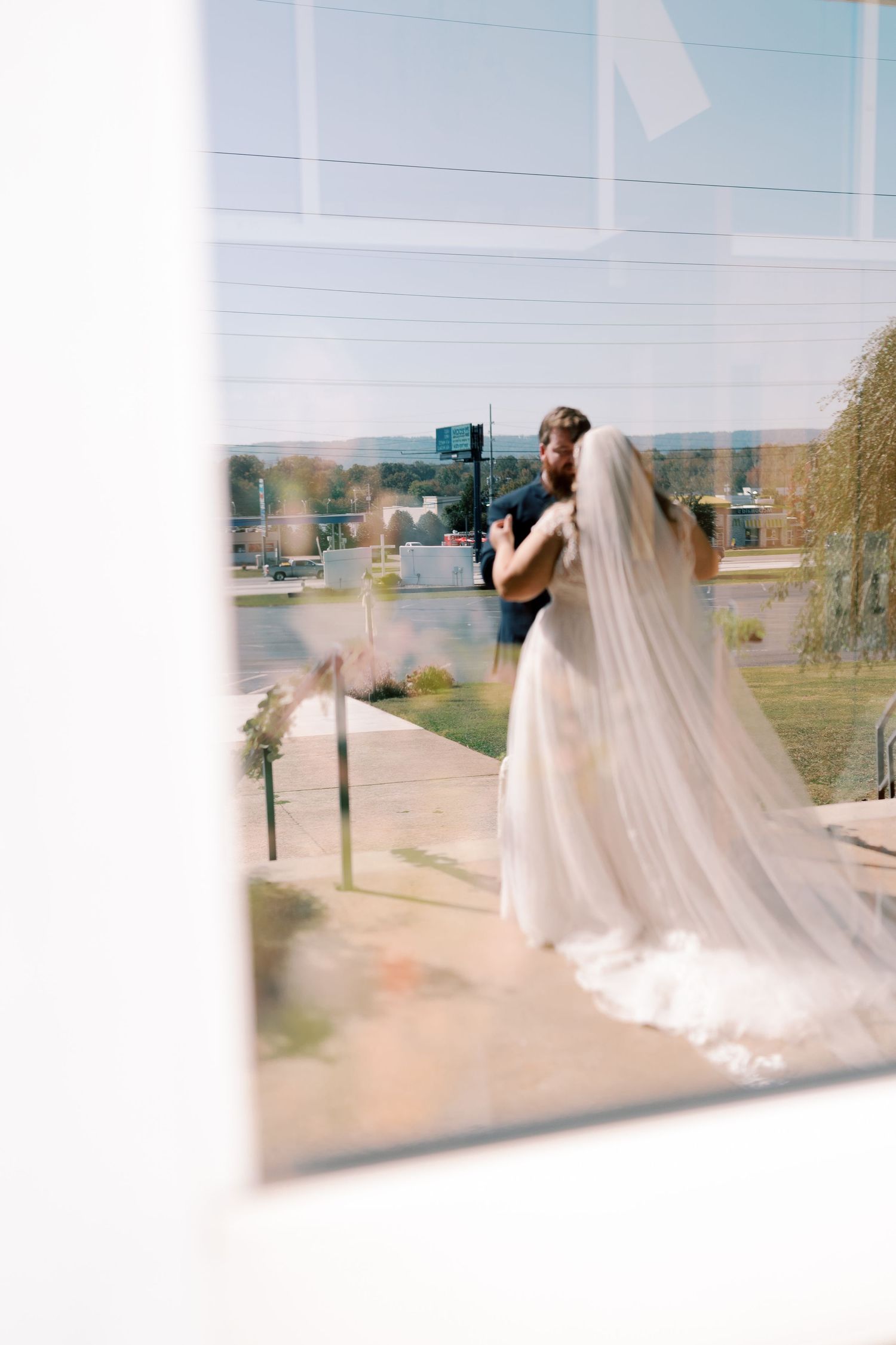 Wedding photographer capturing bride through window reflection.