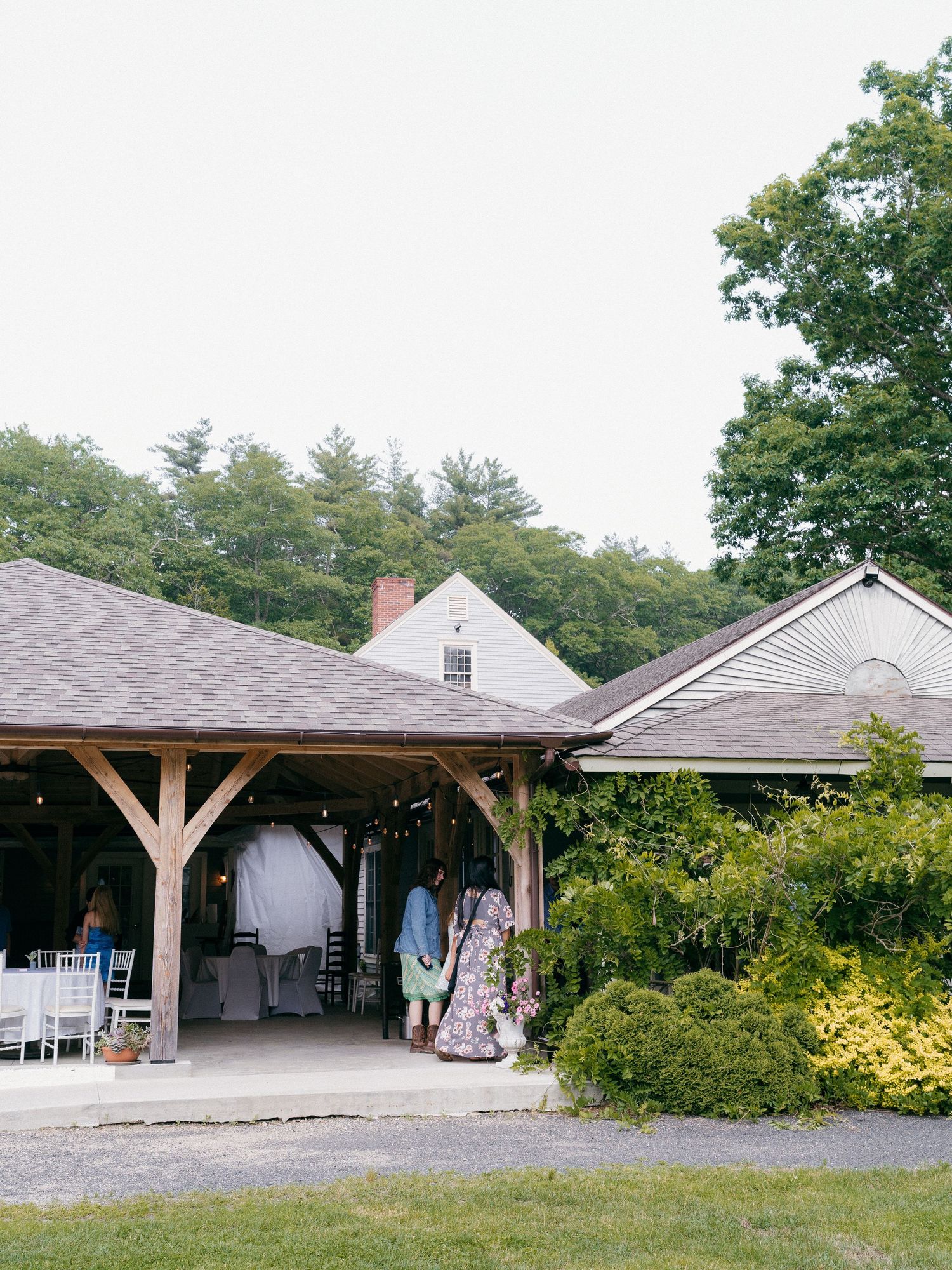 Exterior view of white wedding venue buildings with covered porches and landscaping.