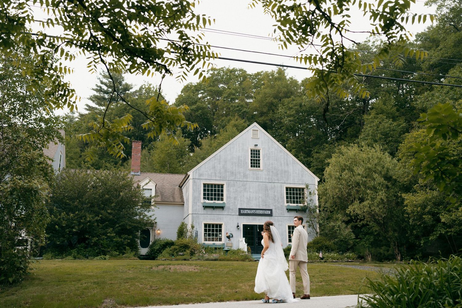 White farmhouse wedding venue with beautiful landscaping and trees.