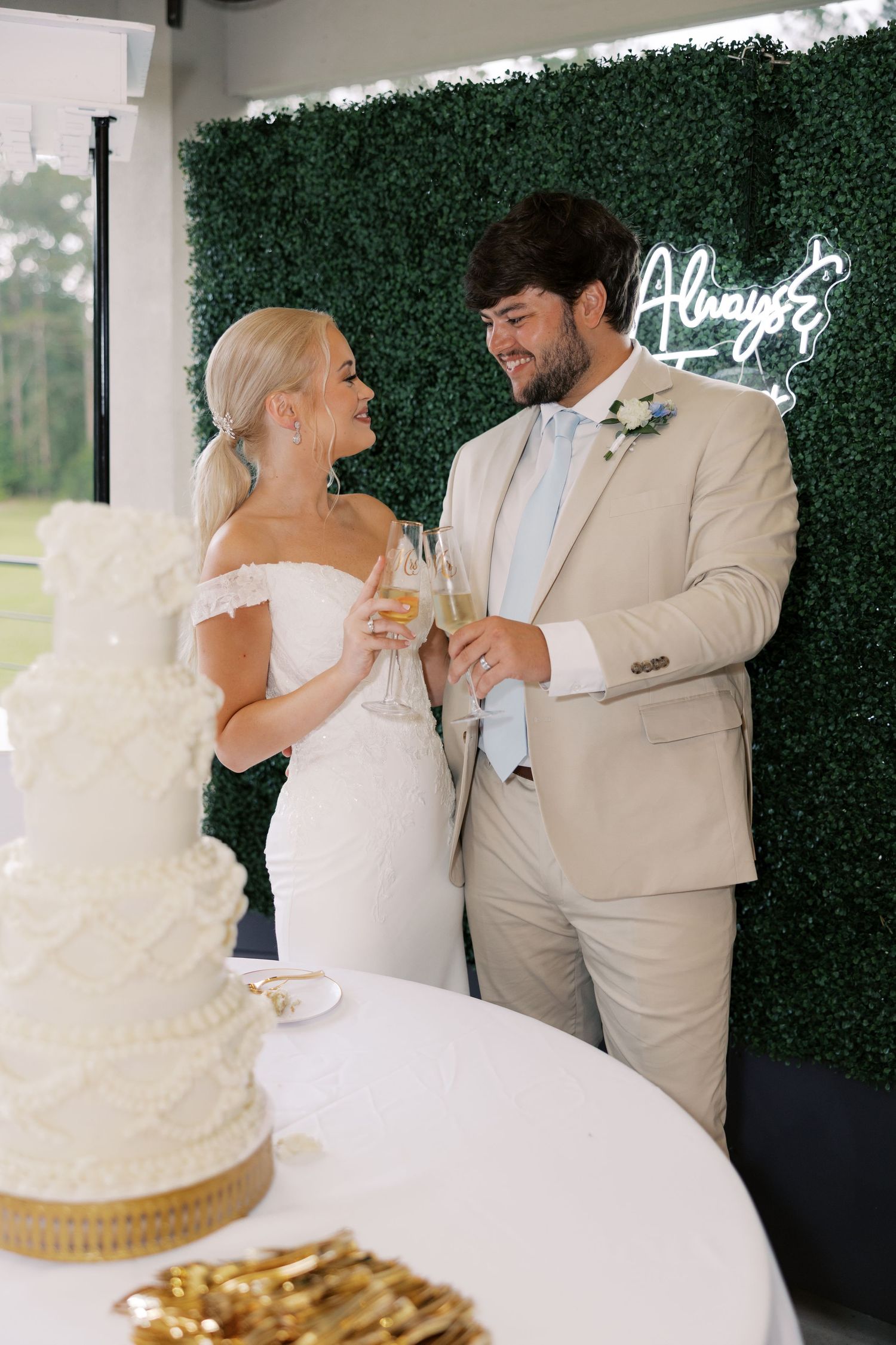 A couple shares a playful moment while cutting their wedding cake at the reception.