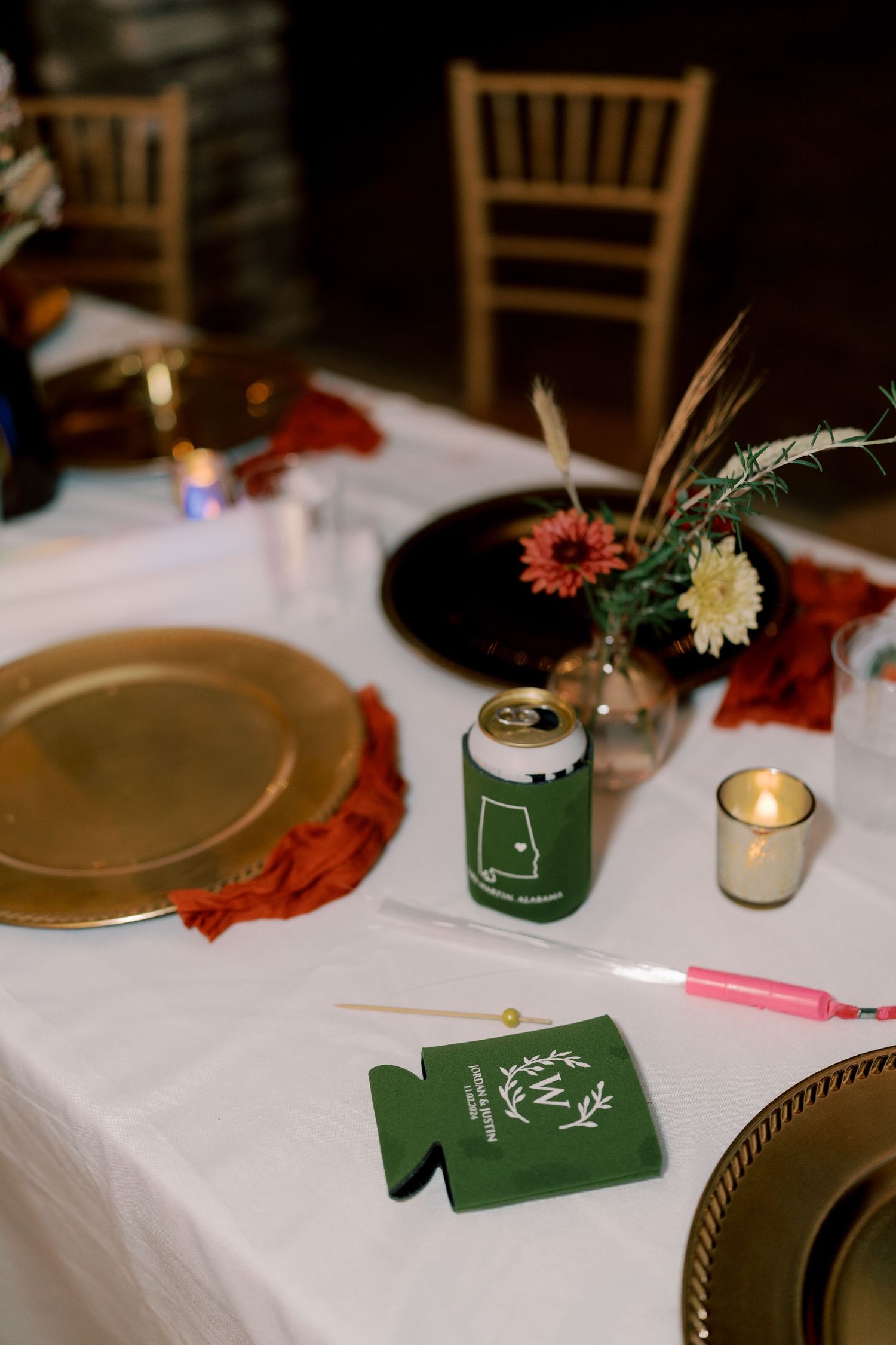 Wedding reception table details with green accents, candles and gold charger plates.