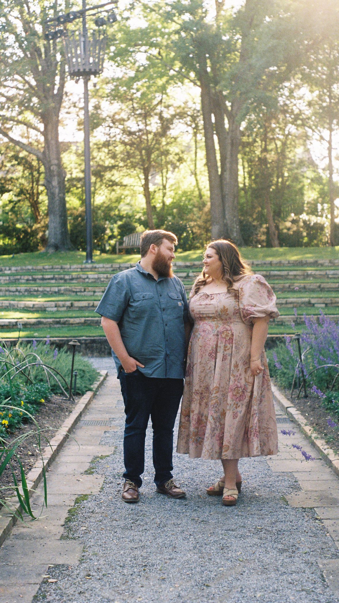 Couple walking together on a garden path during golden hour.