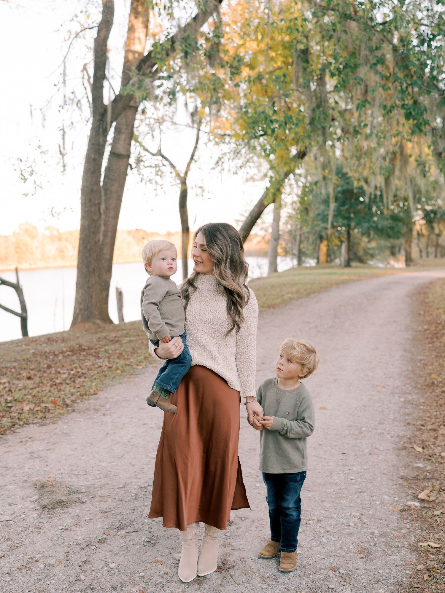 Family walking together on scenic autumn path near water.