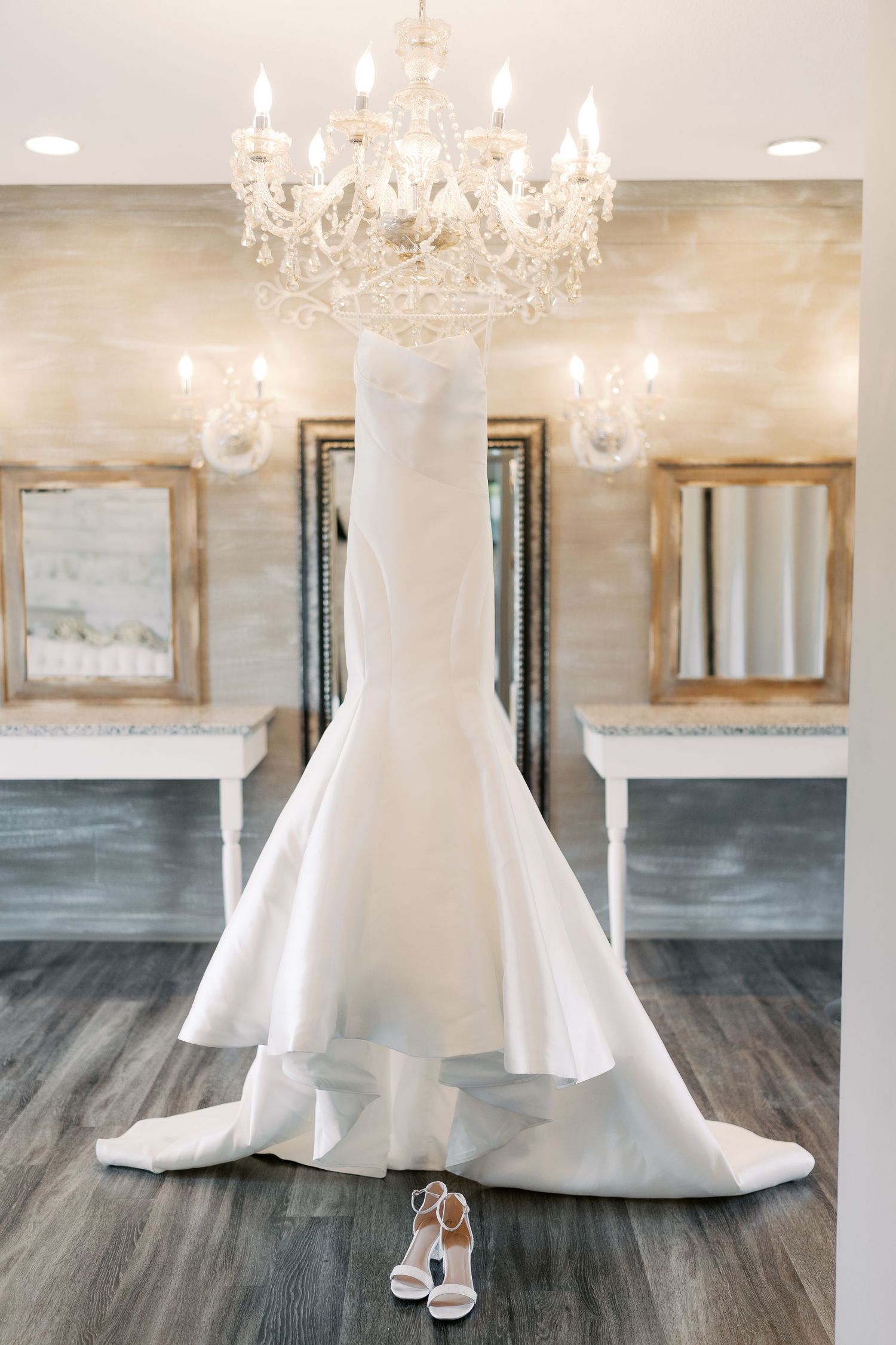 White ballgown wedding dress displayed in an elegant room with crystal chandelier and hardwood floors.