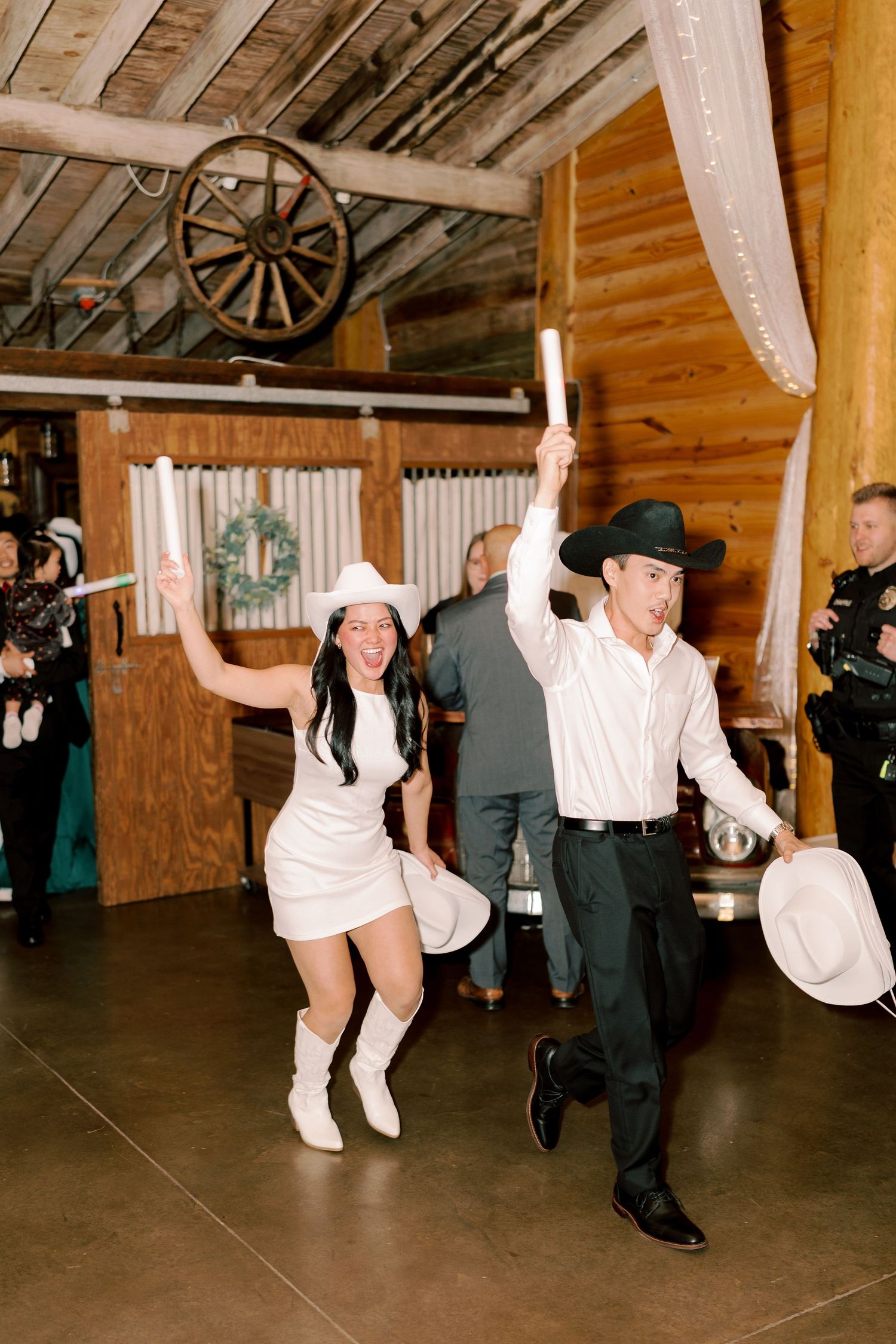 Wedding guests dancing energetically in a rustic wooden barn venue.