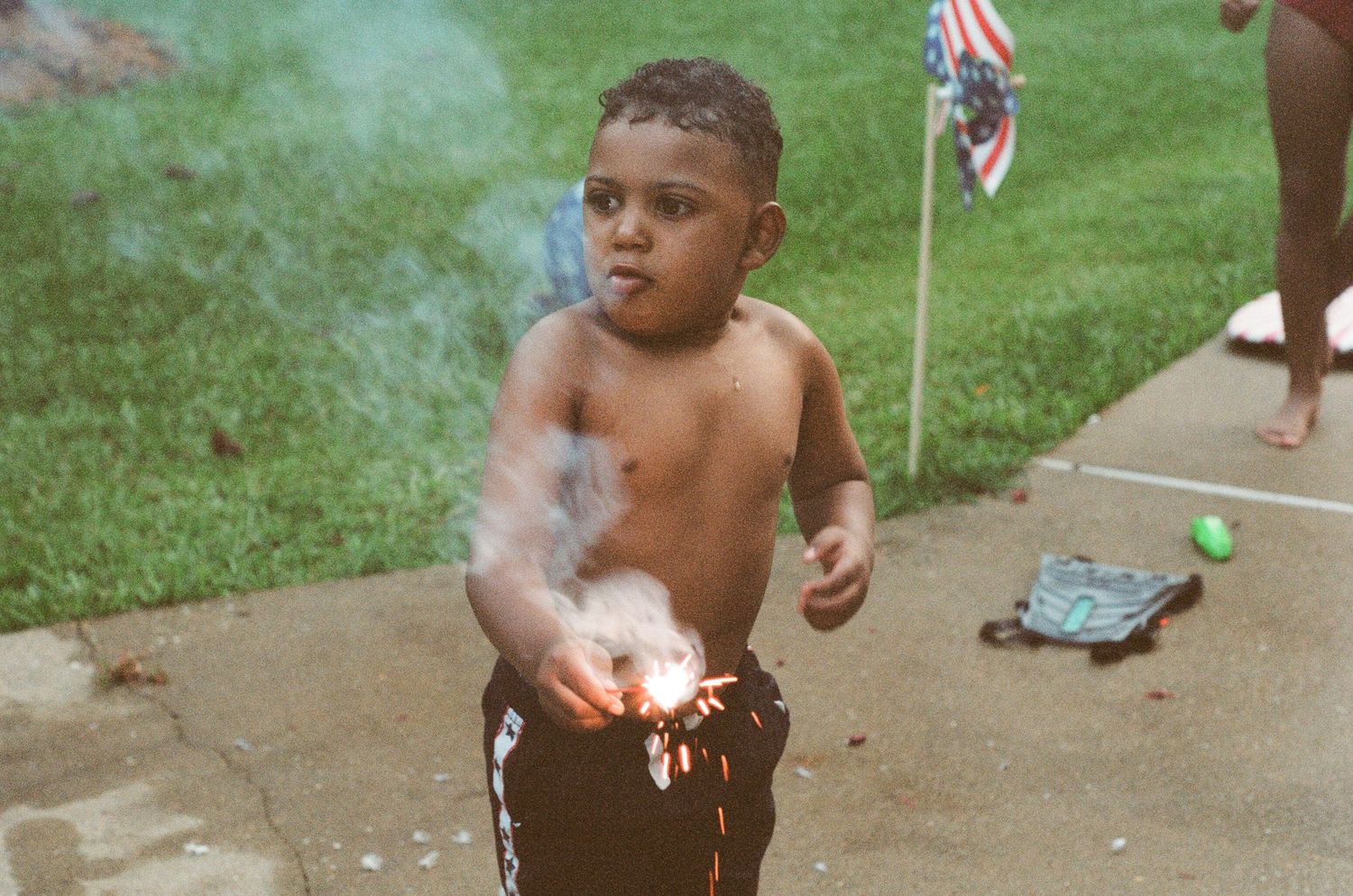 Children playing with sparklers in a backyard on a summer evening.
