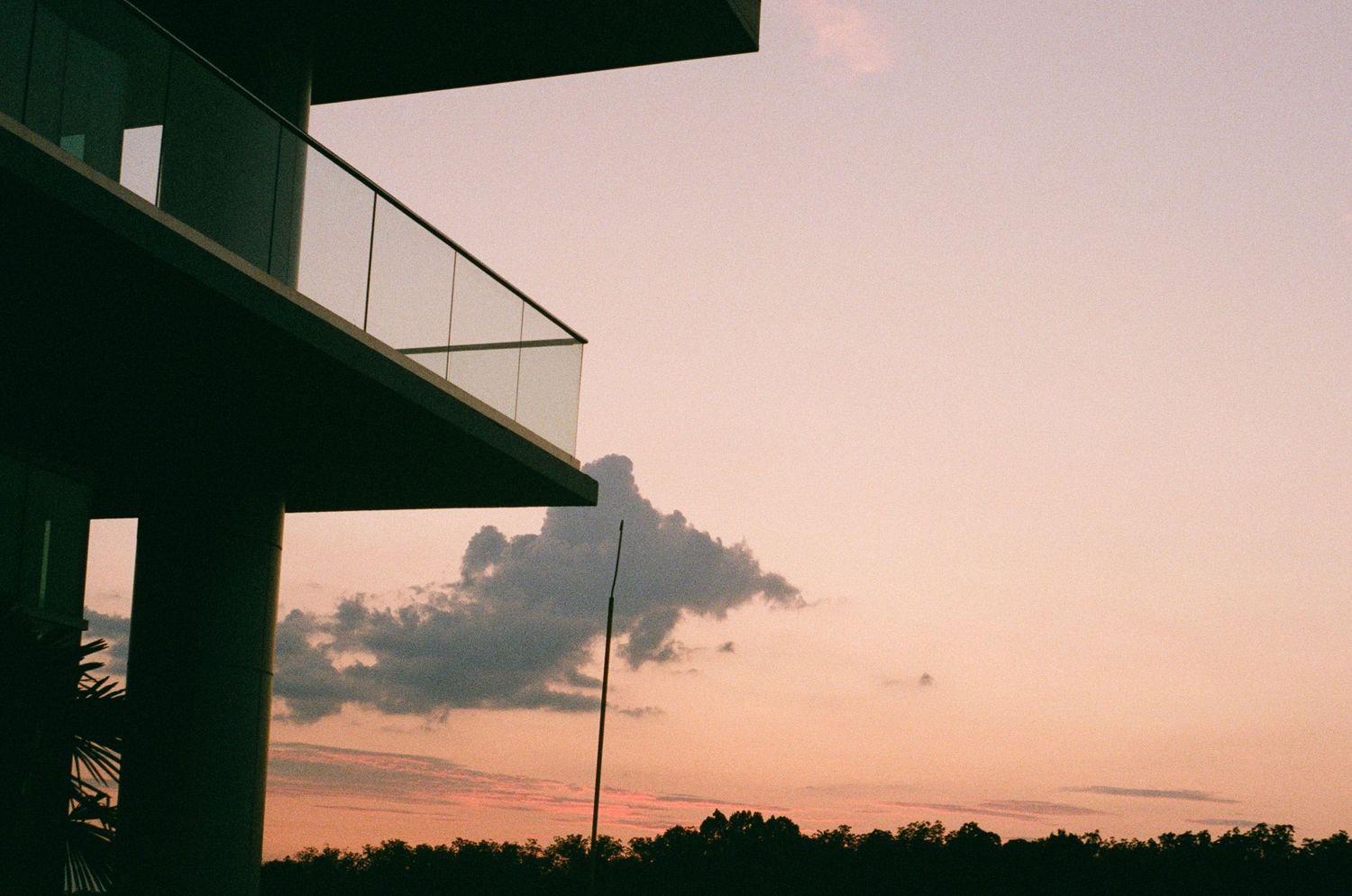 Silhouette of buildings against a pink and orange sunset sky.