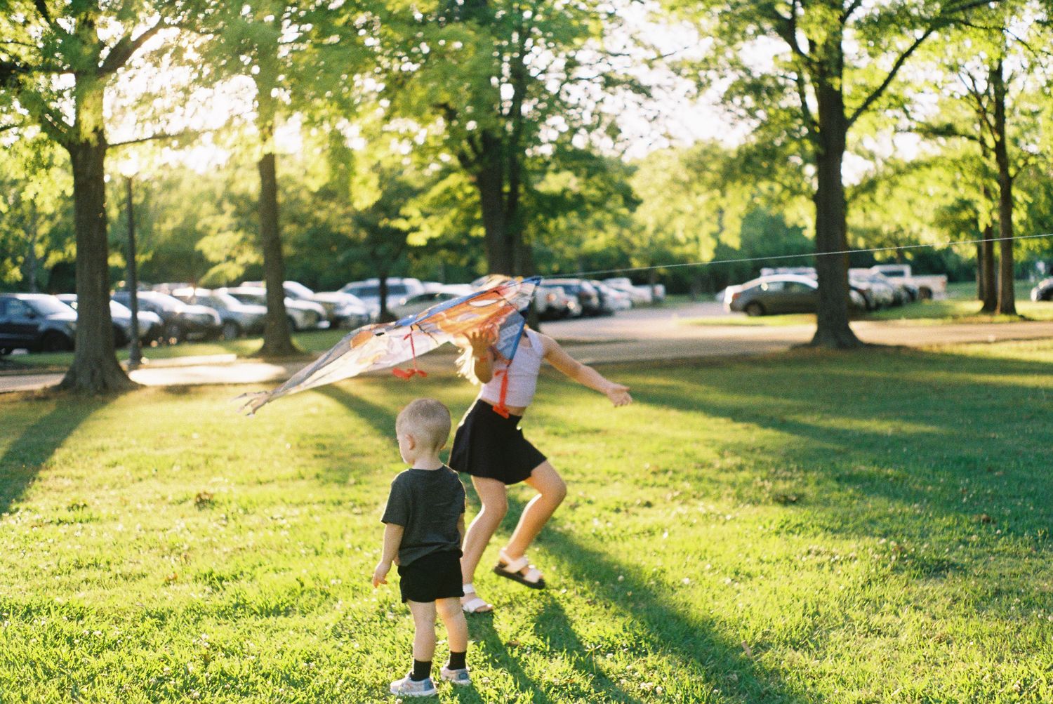 Children playing and running on a grassy hill during sunset.