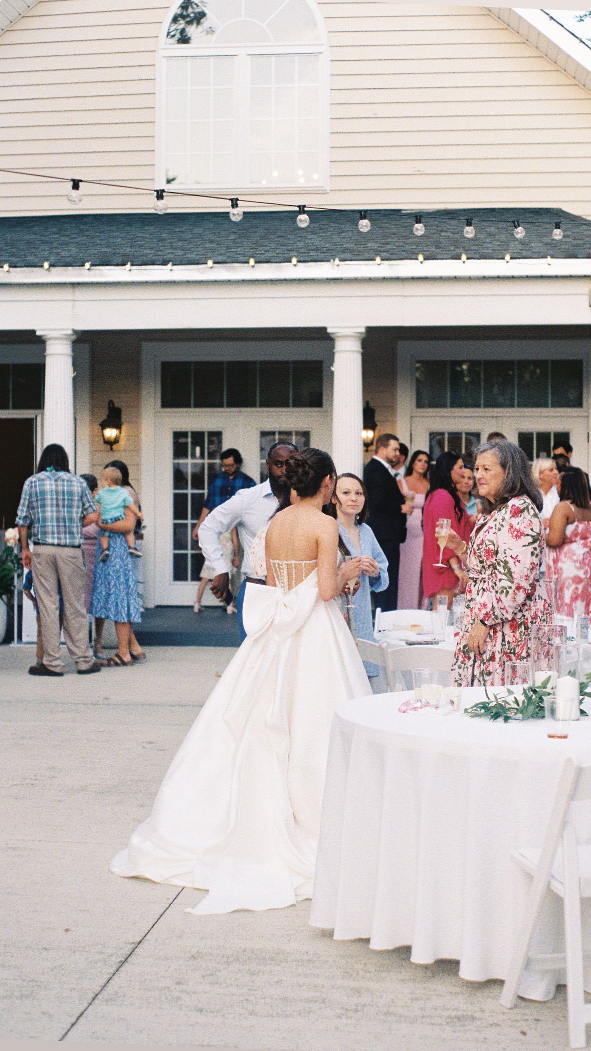Wedding reception setup outdoors with white tables and decorations.