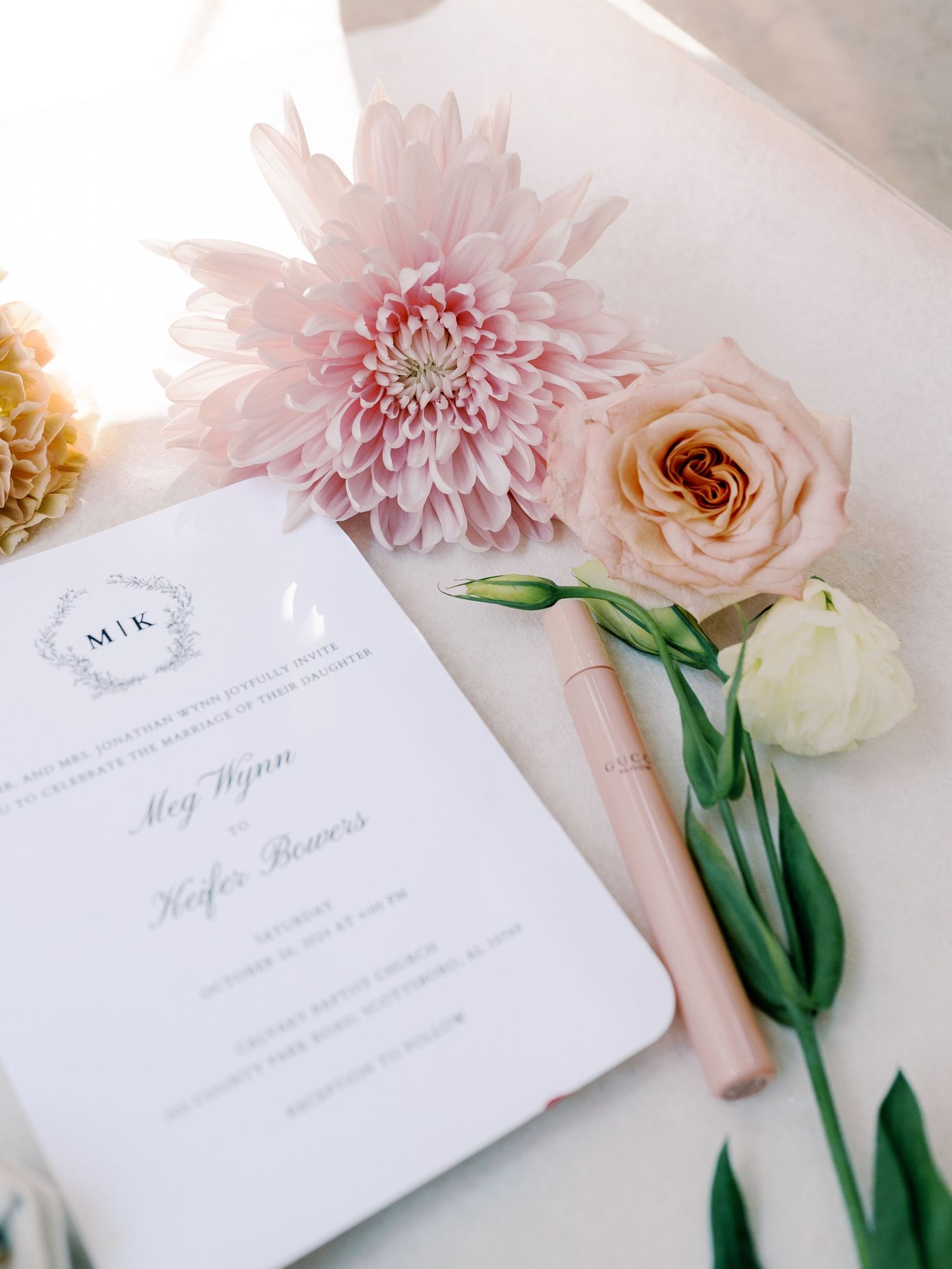 Wedding invitation with pink dahlia and rose floral decorations on white background.