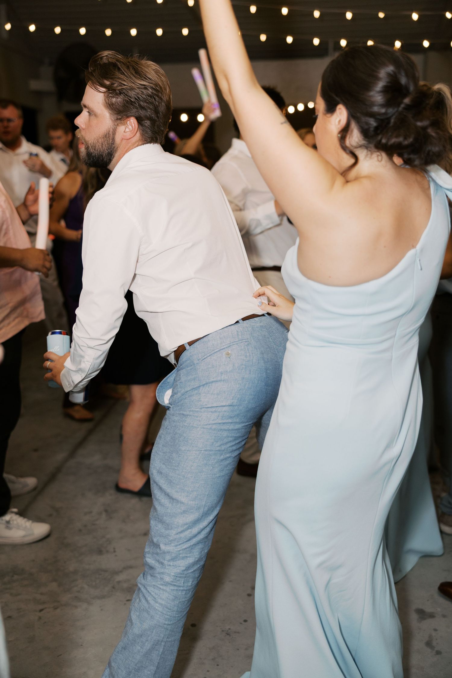 Wedding guests dancing and celebrating on the dance floor under twinkling lights.