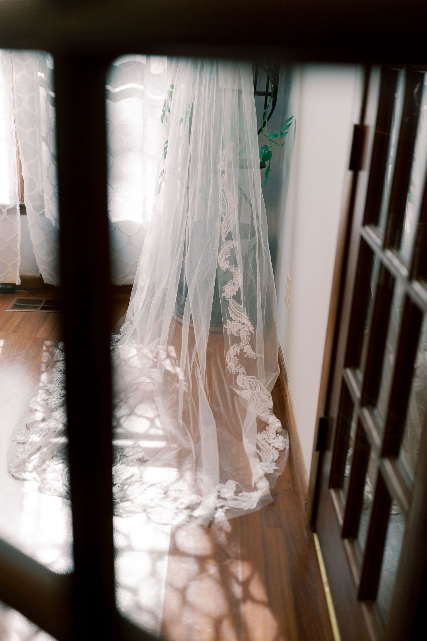 Wedding veil with lace details creating shadow patterns on hardwood floor.