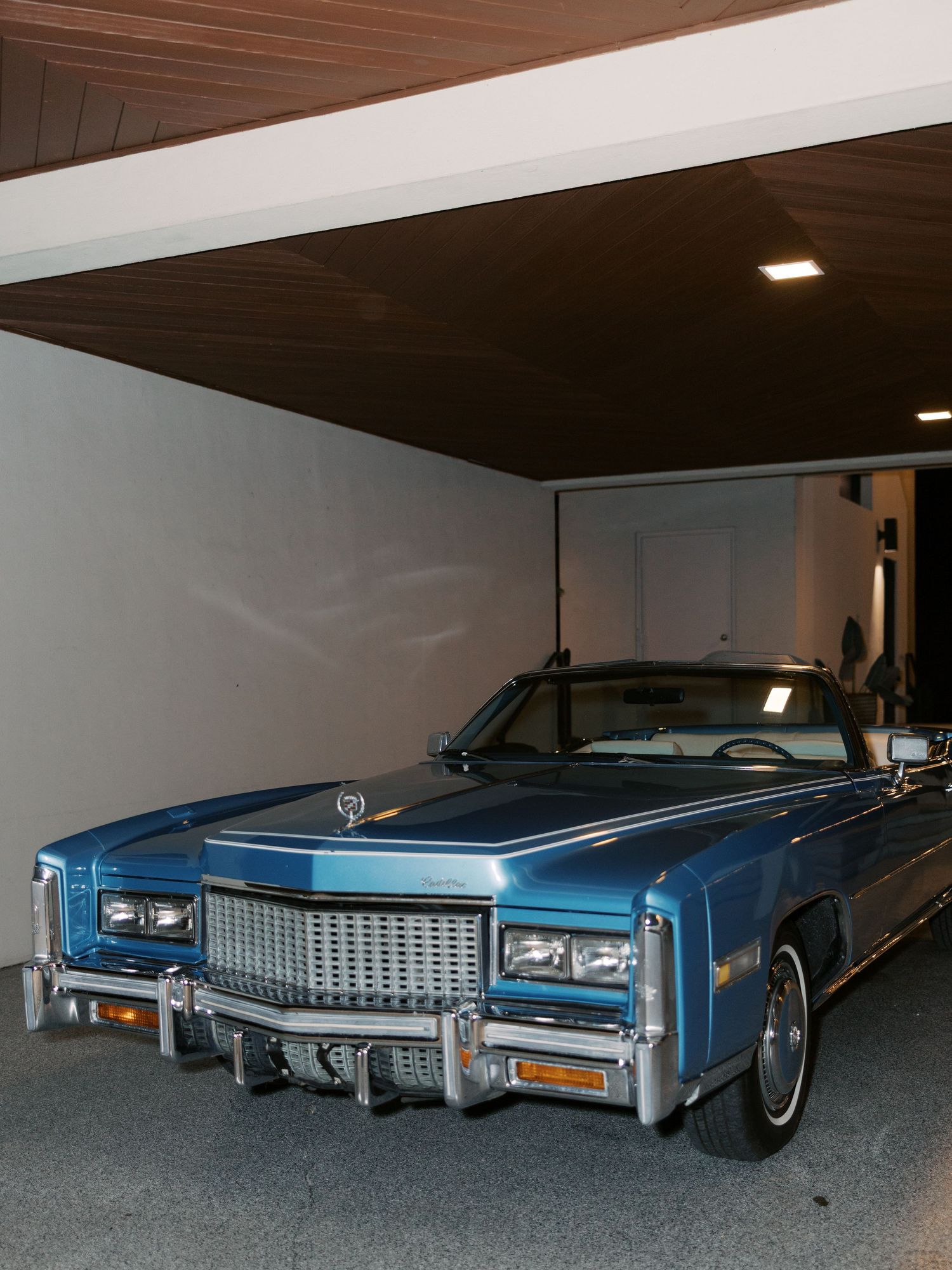 Row of vintage blue Cadillac cars displayed in a garage or showroom.