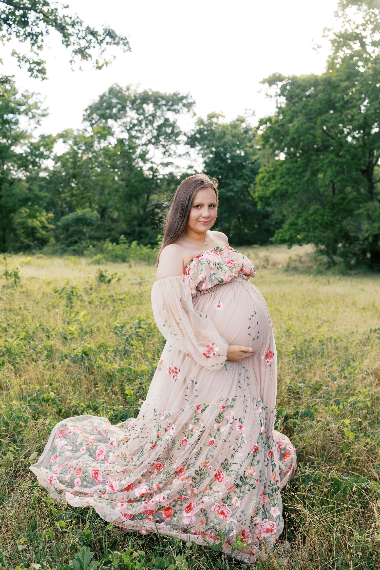 Delicate floral dress billows gracefully in a summer field surrounded by lush greenery.