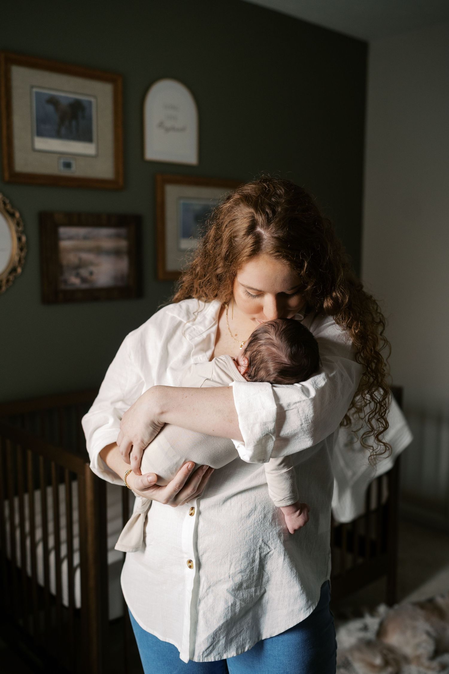 Intimate lifestyle photography captures tender moments with a baby in a nursery setting.