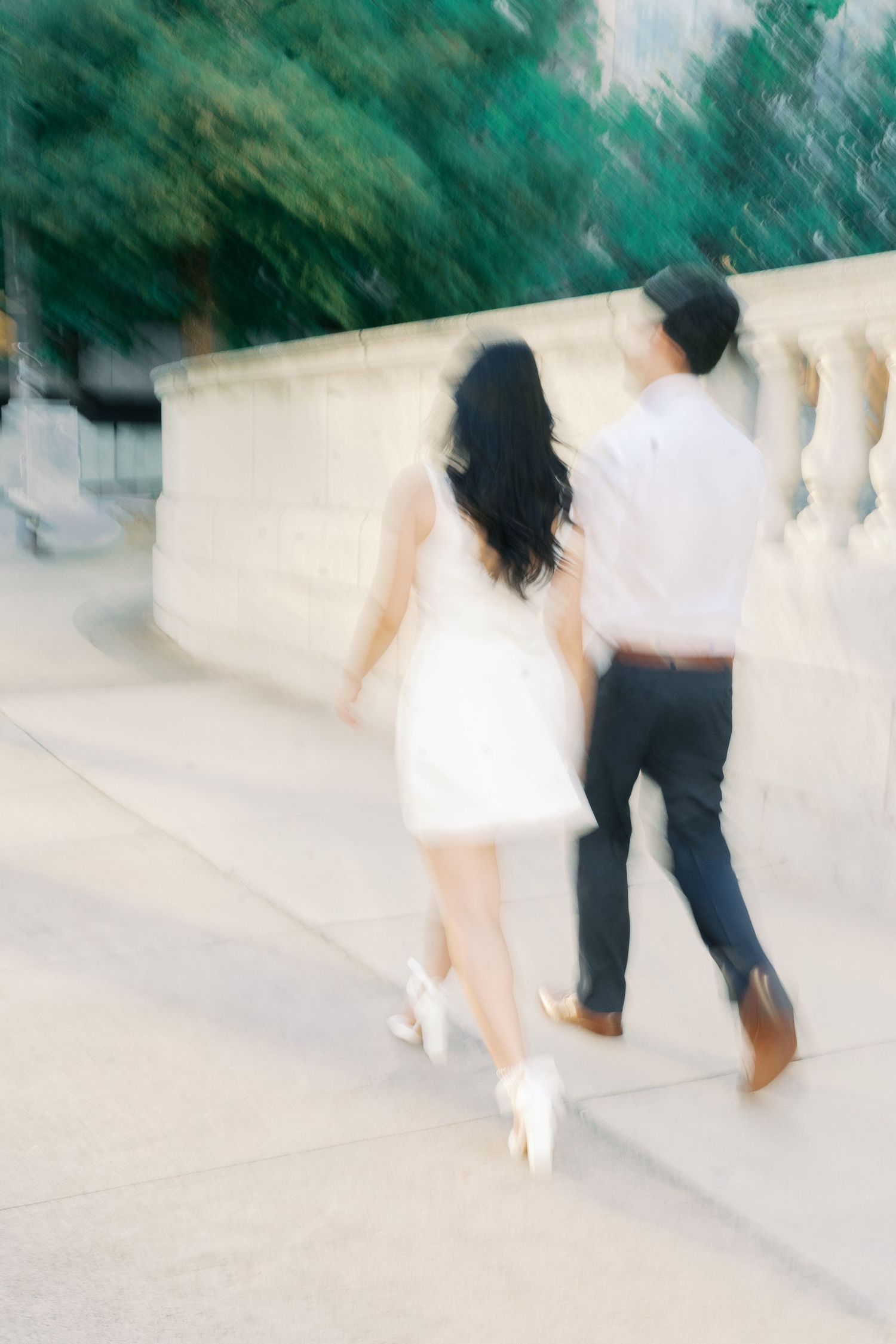 Artistic motion blur capture of couple walking on white stone steps.