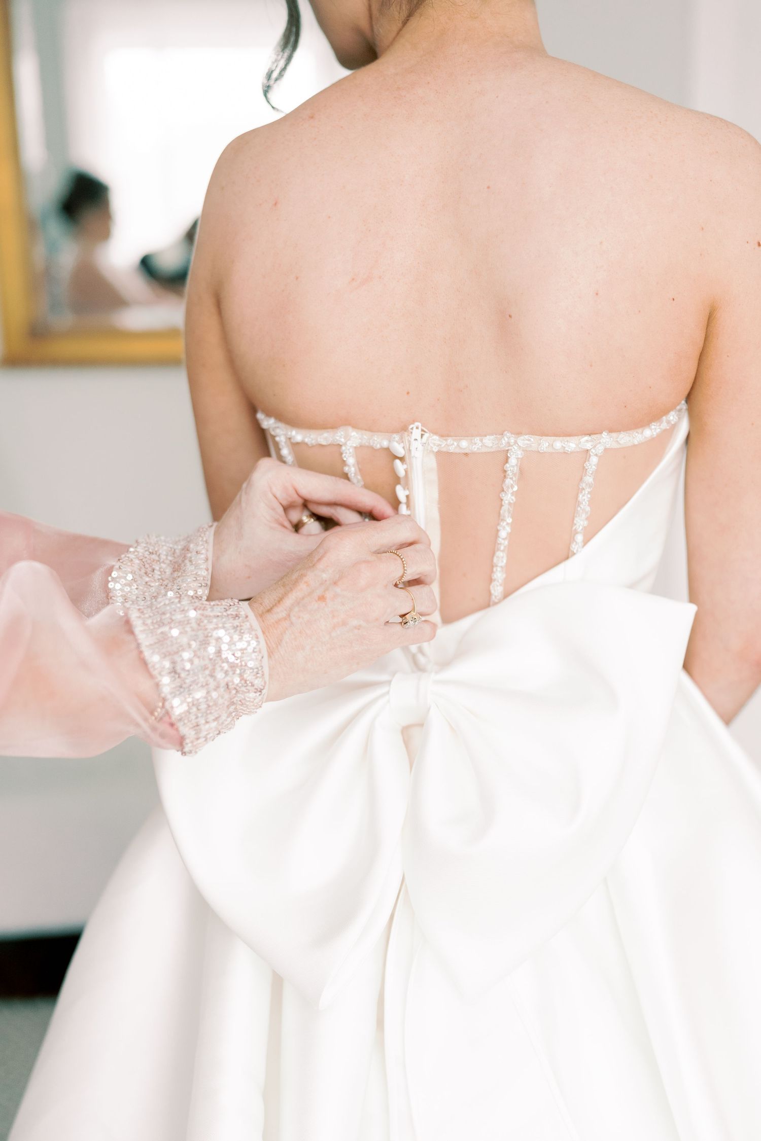 Close-up details of a white wedding dress showing delicate beading and buttons.