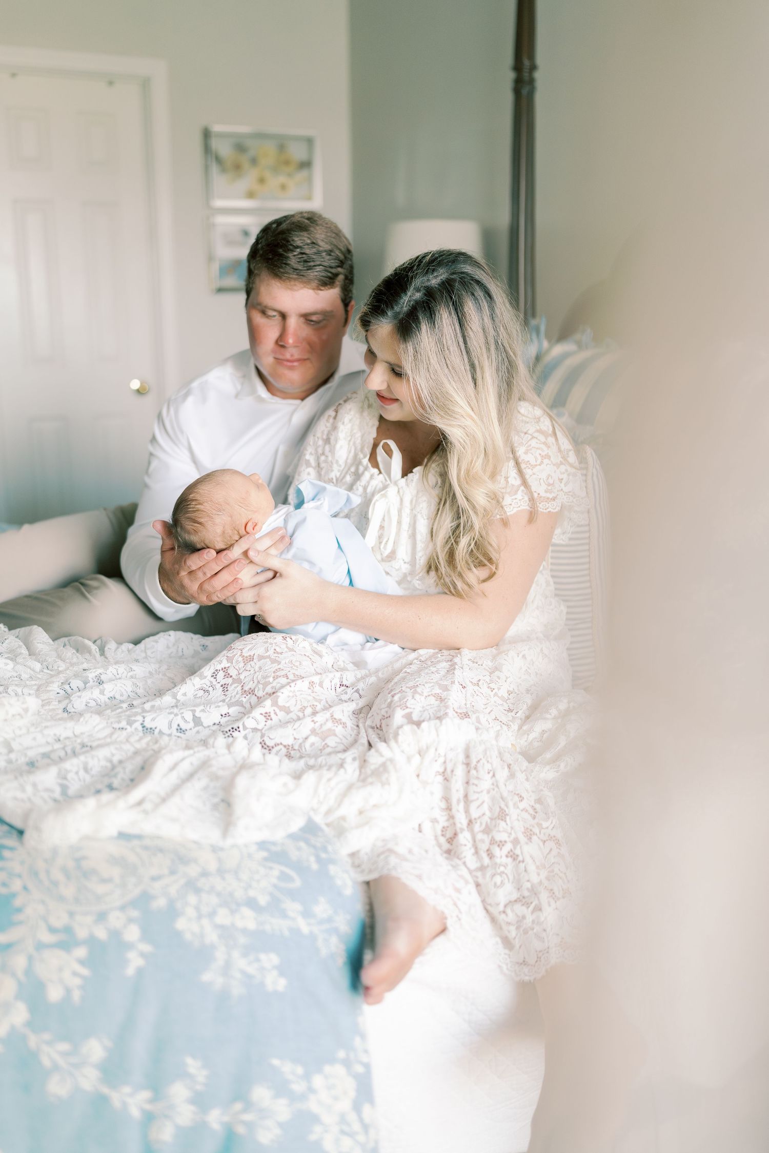 Parents share intimate moment with newborn on bed with blue accents.