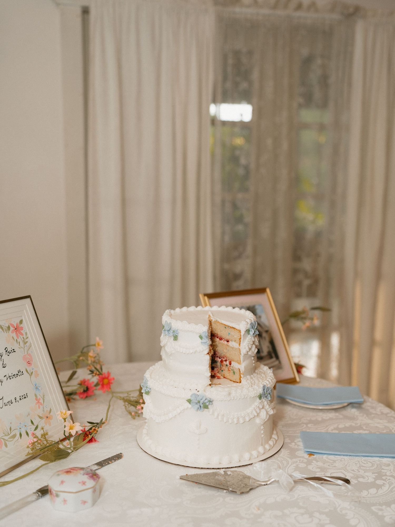 Wedding cake display on white tablecloth with decorative cards and place settings.