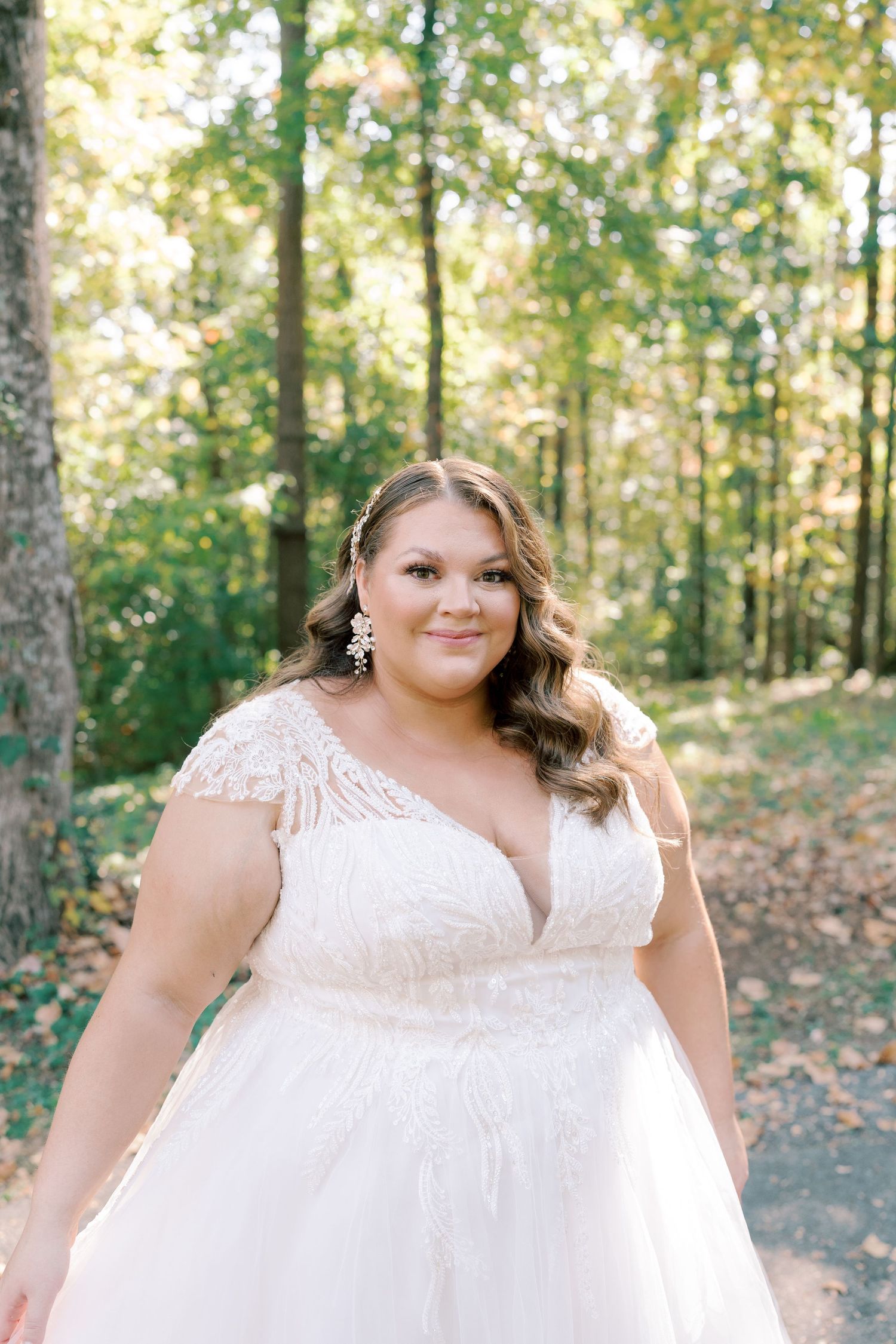 Elegant white lace wedding dress with cap sleeves photographed in natural outdoor setting.
