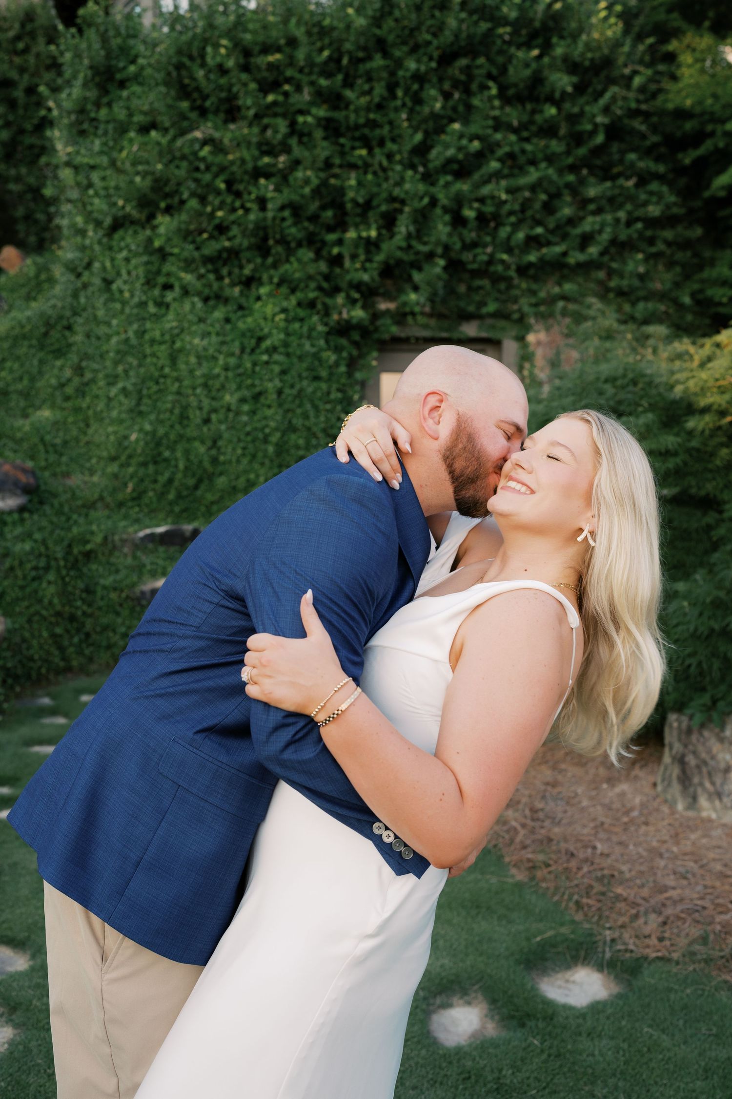 Couple sharing romantic dip pose on garden lawn.