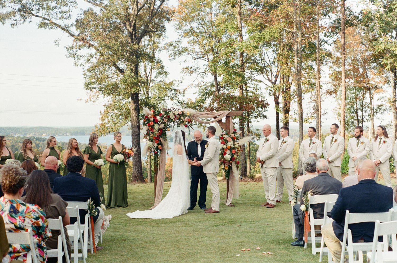 Outdoor wedding ceremony setup with white chairs and floral arrangements overlooking a scenic view.