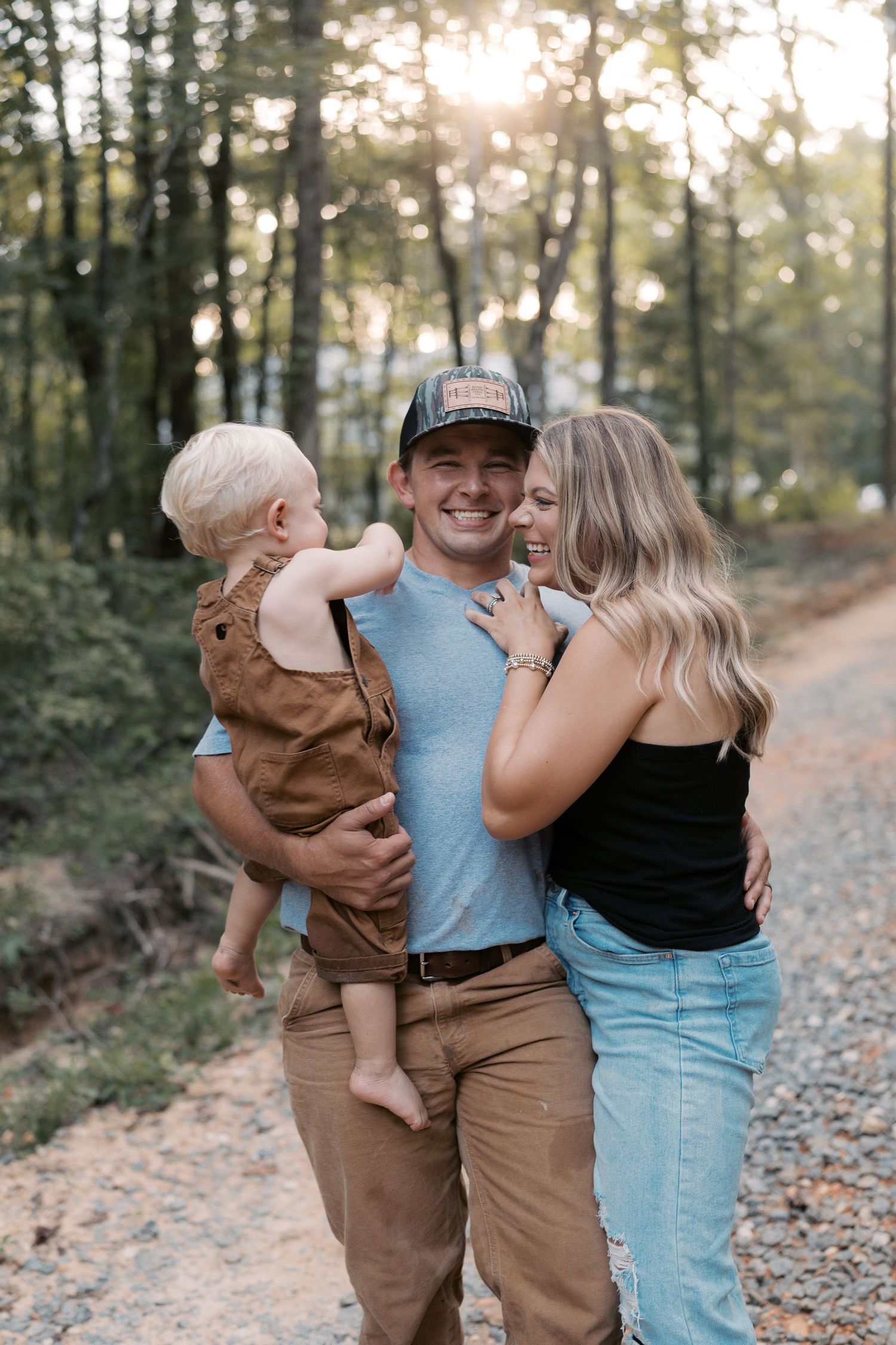 A family shares joyful moments together on a sunlit forest path.