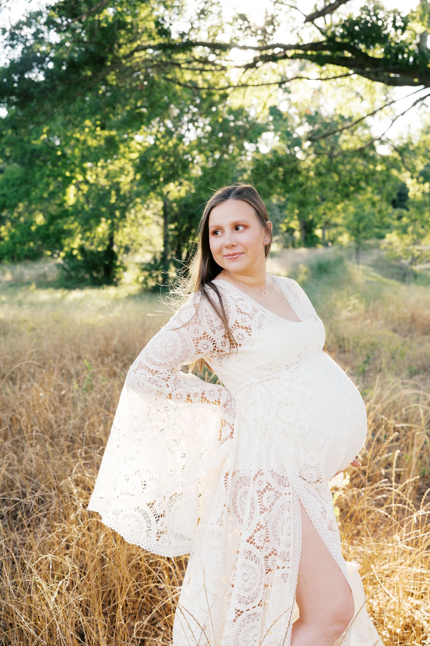 Delicate white lace dress creates ethereal movement against golden grass backdrop.