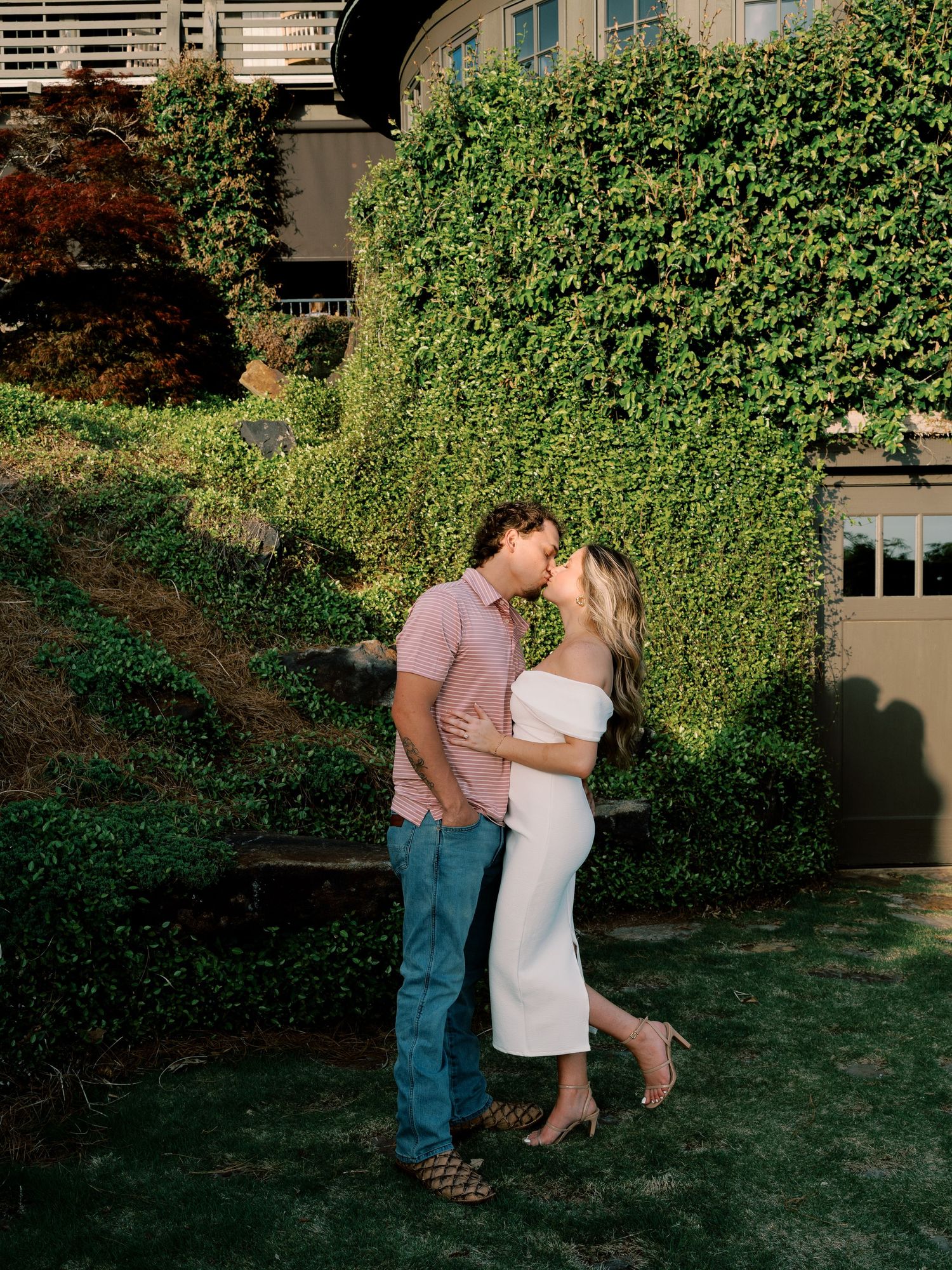 A couple dances together in front of a beautiful garden backdrop.
