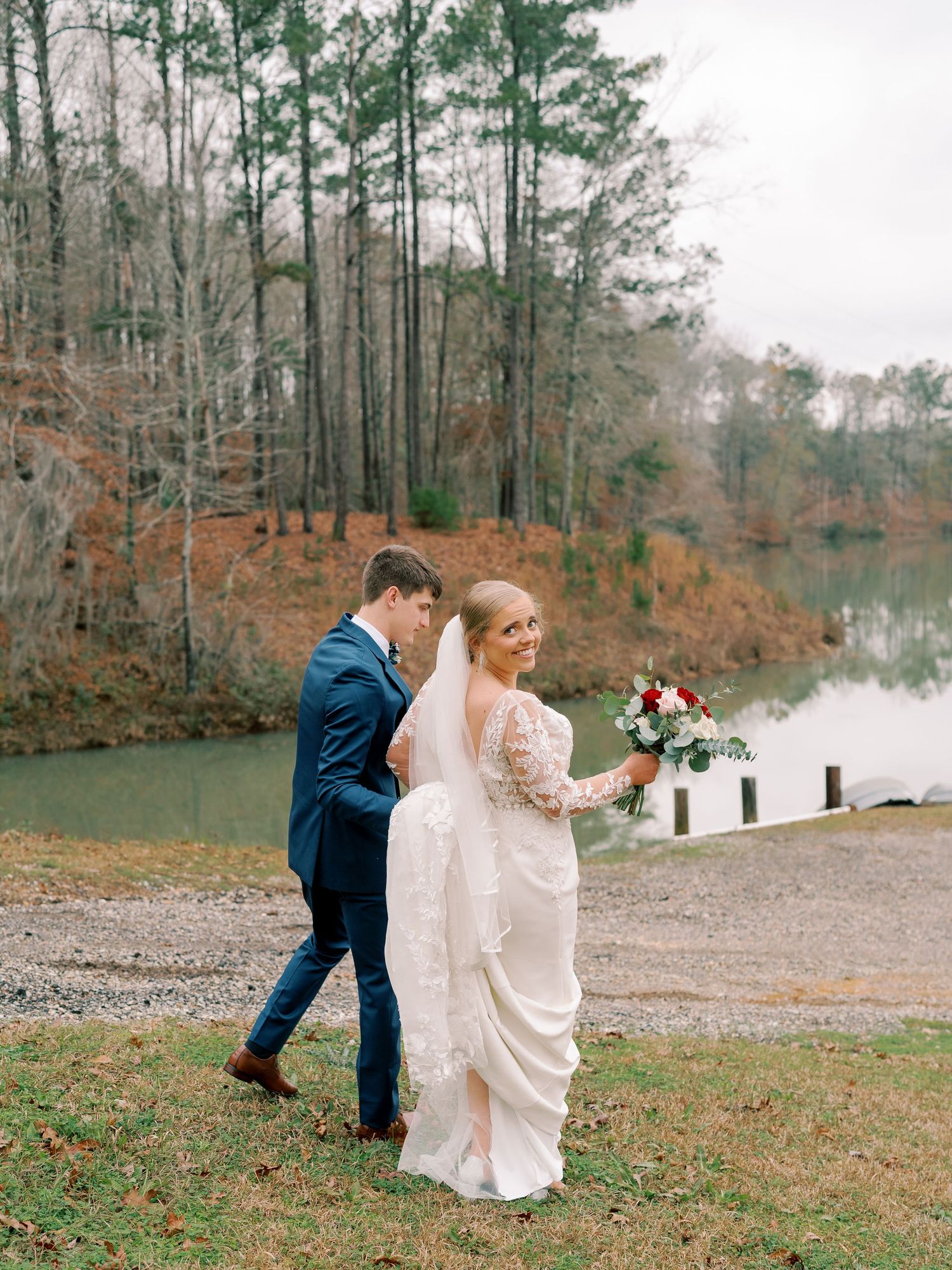Couple shares romantic moment by lake during fall wedding photoshoot.