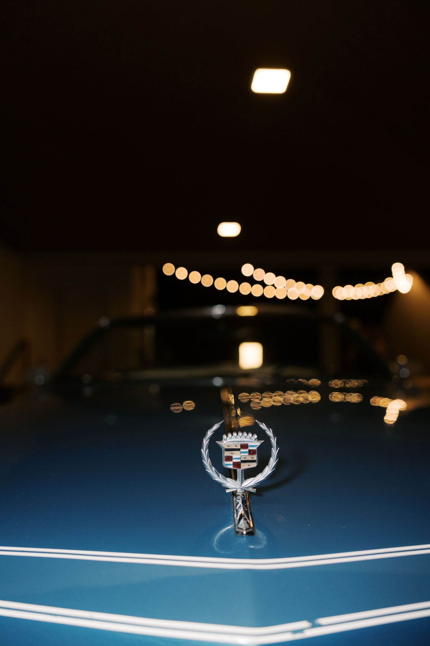 Close-up detail of a vintage Cadillac hood ornament with decorative chrome emblem.