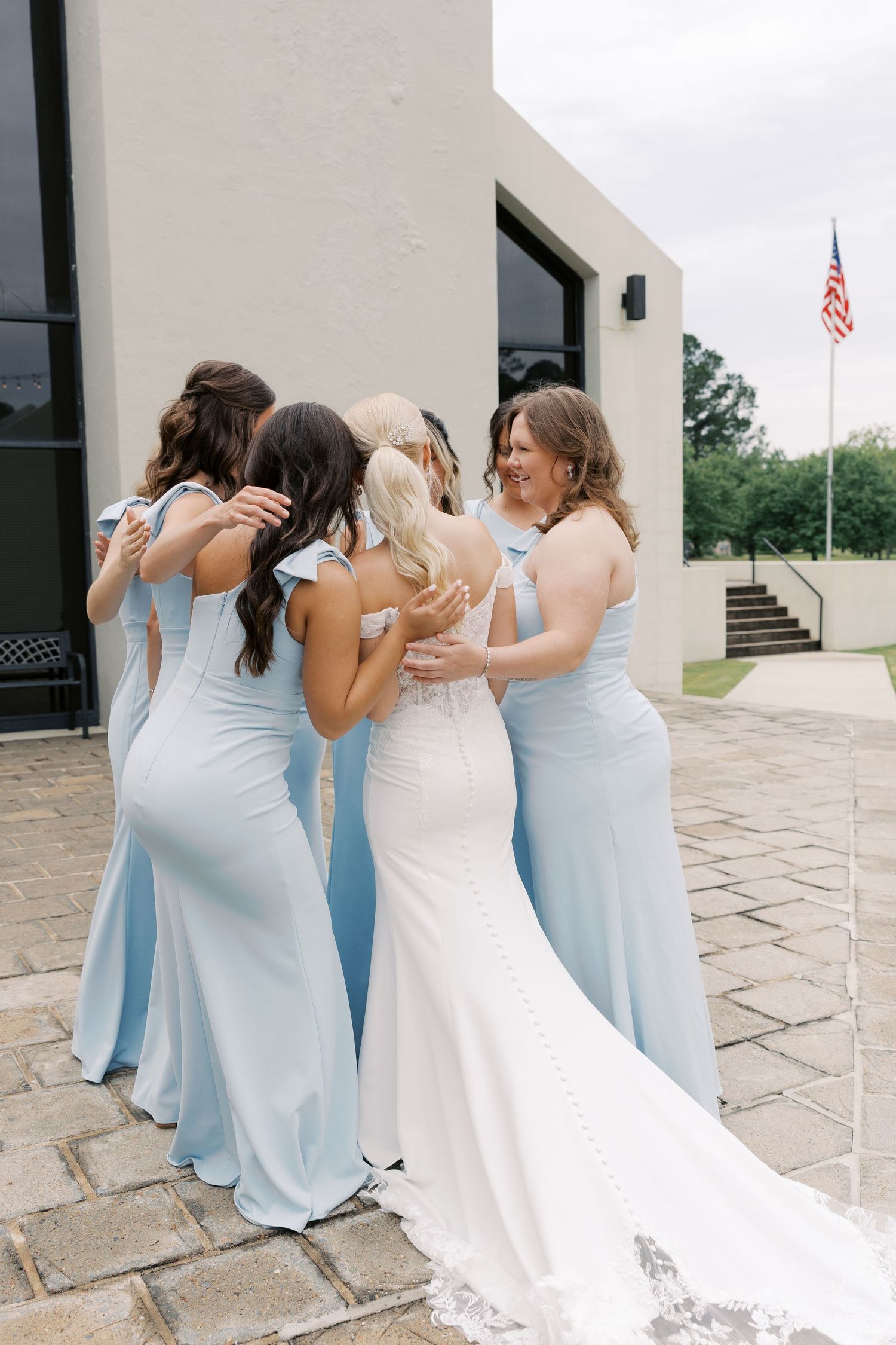 Wedding party in light blue dresses and white gown share joyful reactions during a first look moment.