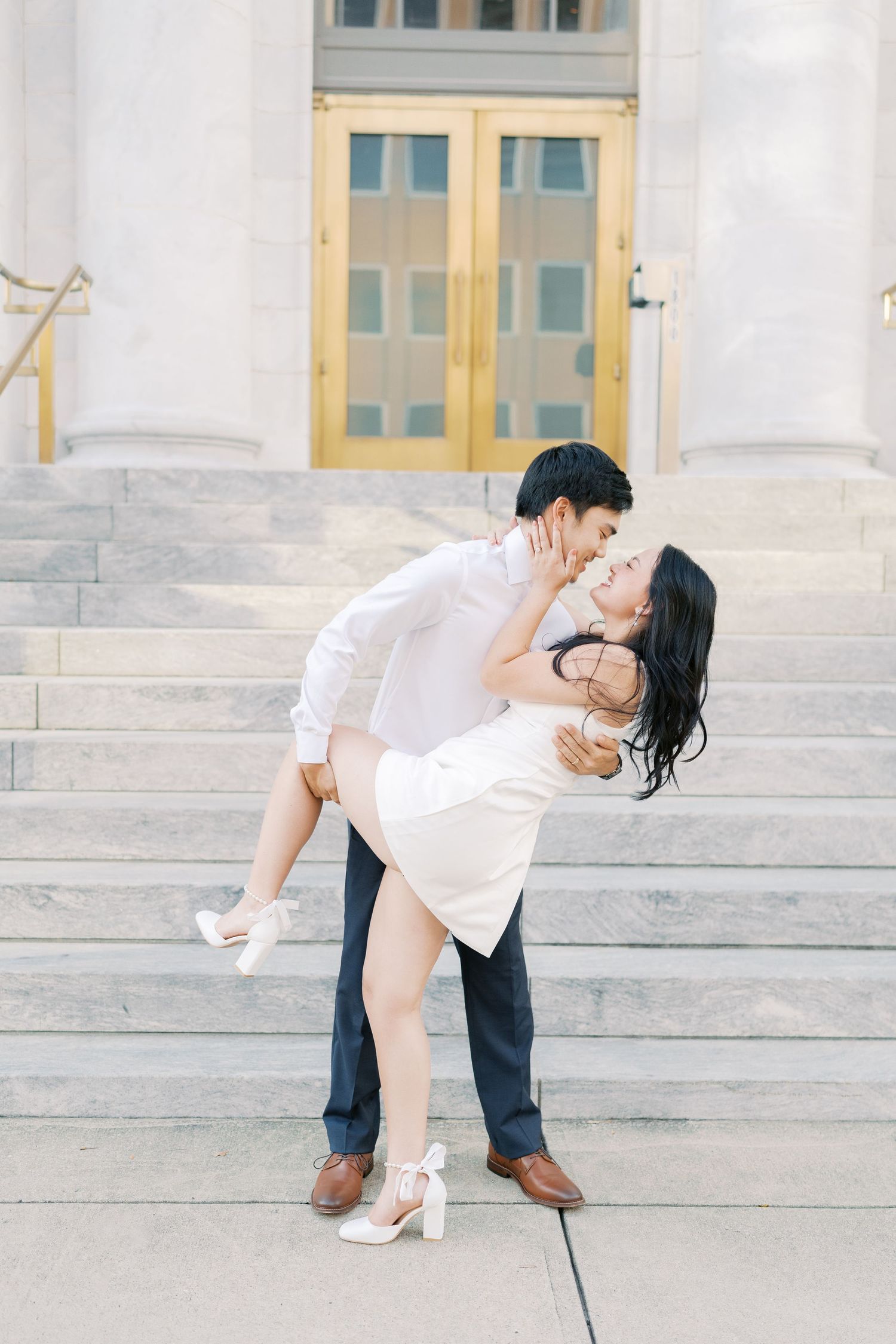 Romantic dance dip sequence photographed against classic white building facade.