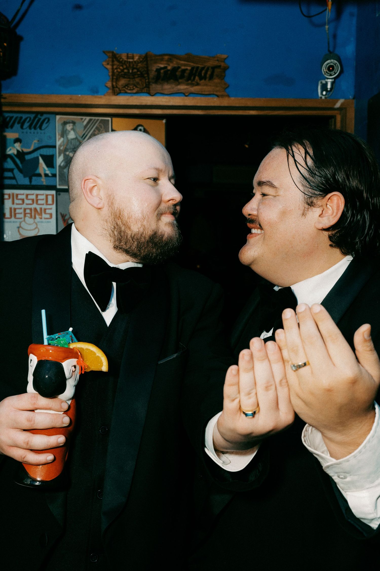 Two people in formal wear sharing drinks and conversation at a bar.