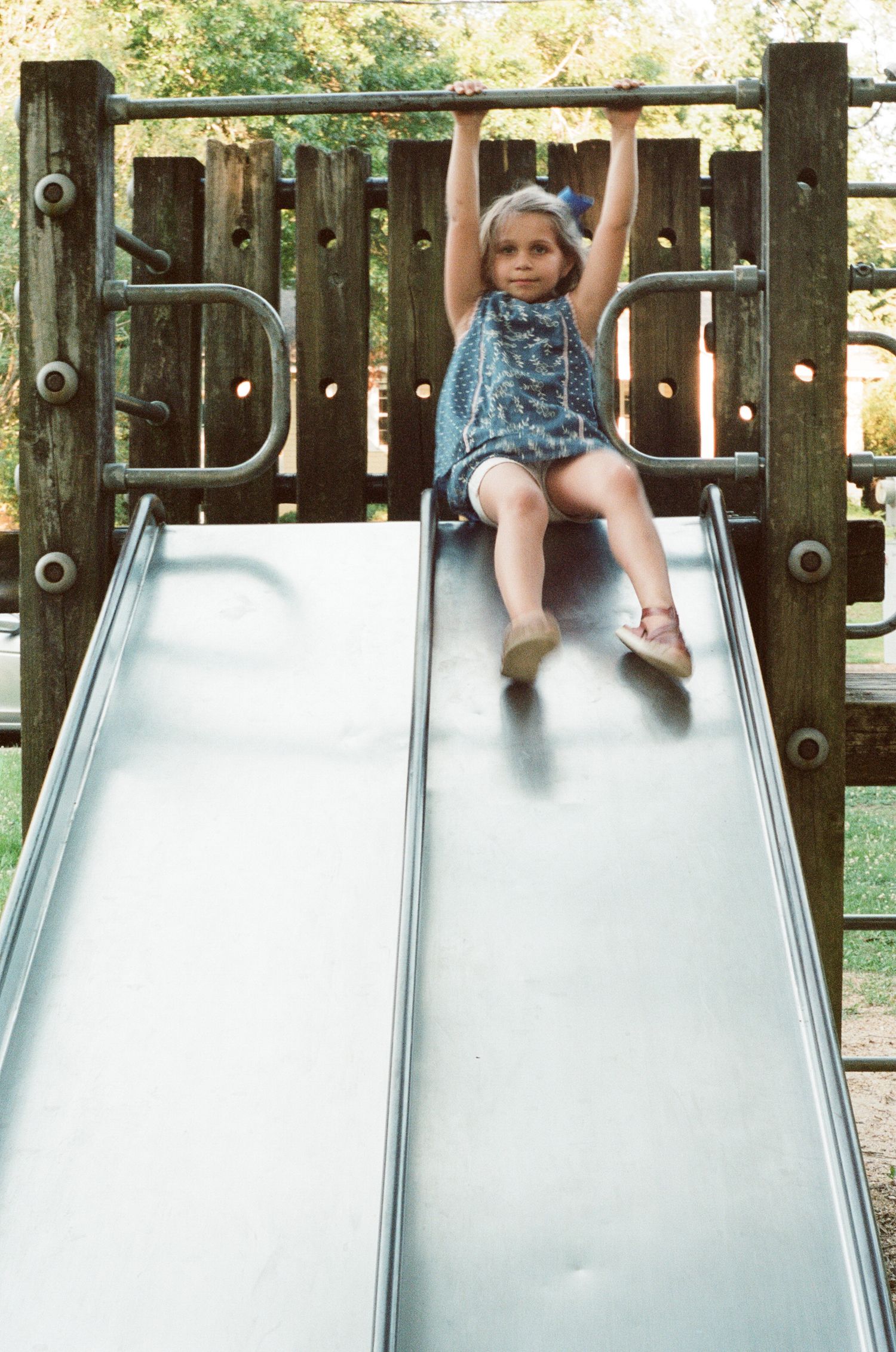 Children playing on playground slides in a wooden play structure.