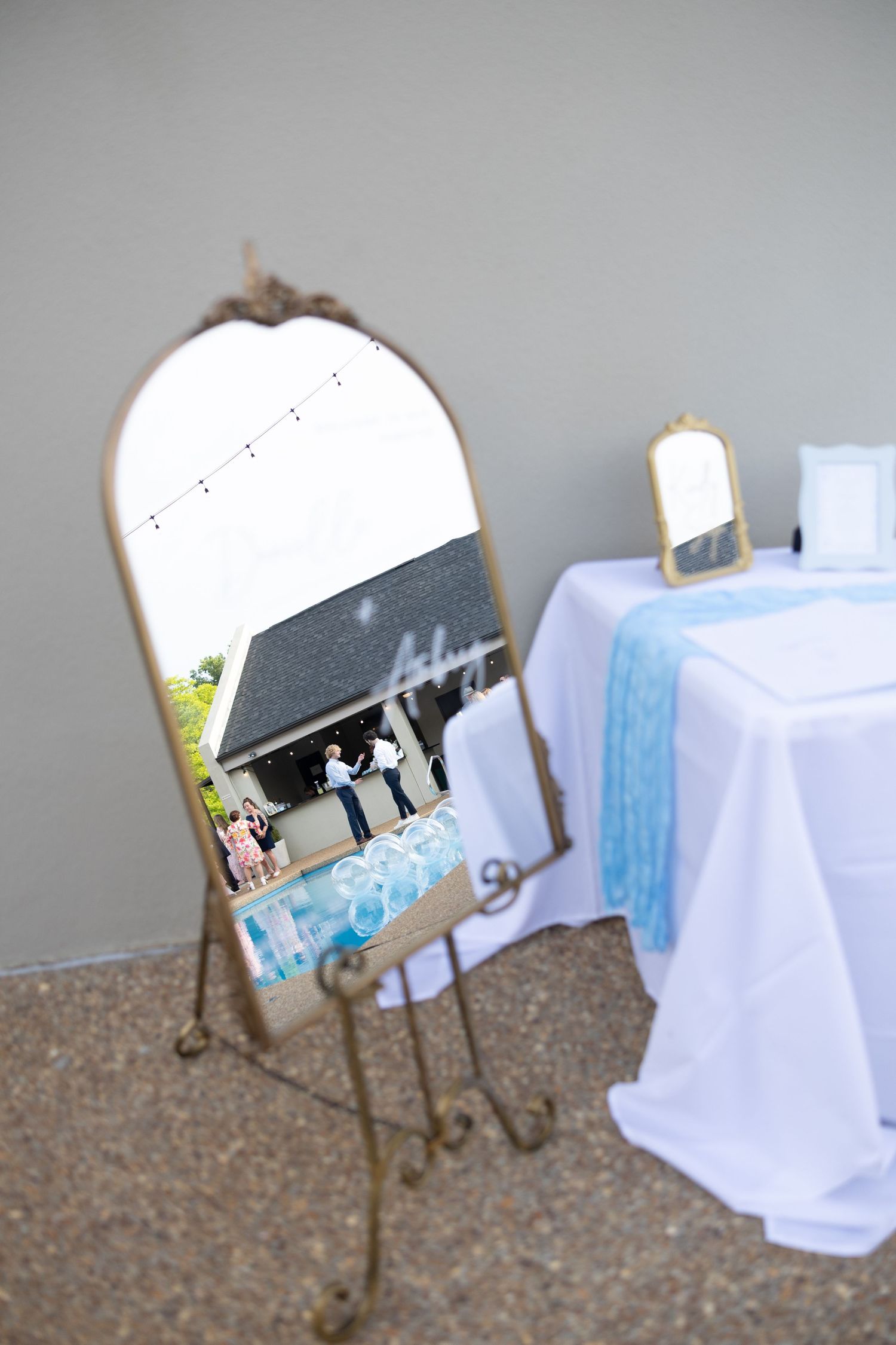 Wedding welcome sign displayed on an ornate metal stand with white and blue decor.