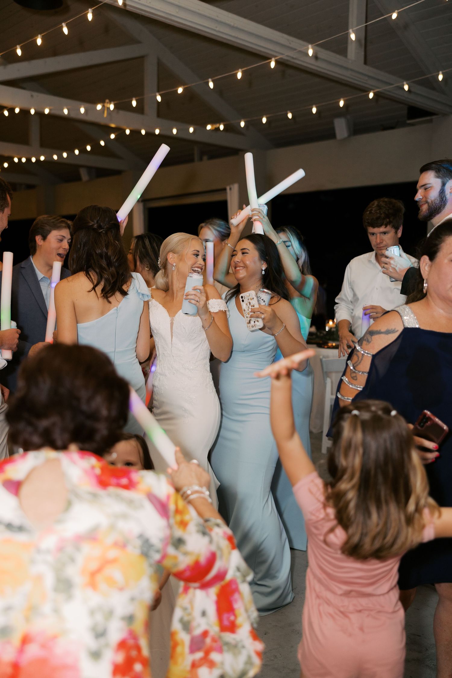 Wedding reception dance floor with guests celebrating under string lights.