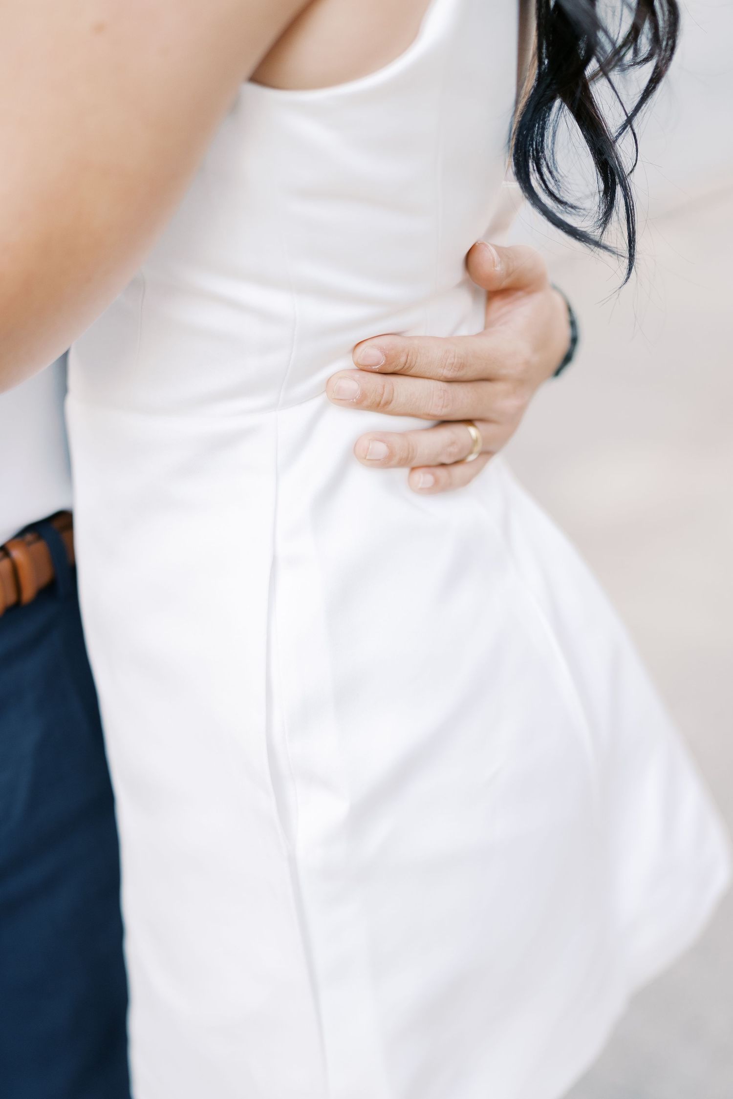 Close-up shots of a couple in white clothing sharing intimate moments against a bright background.