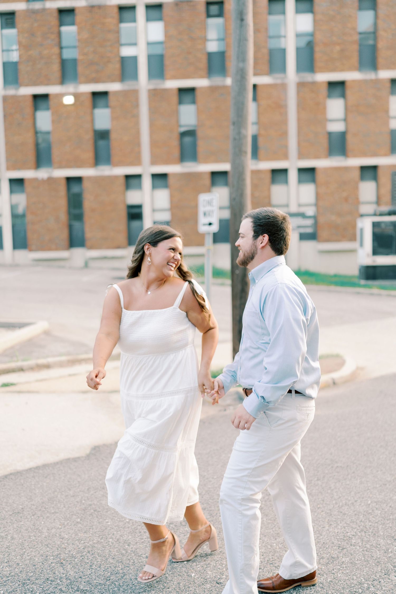 A couple dances and spins together on a paved area wearing coordinating white outfits.