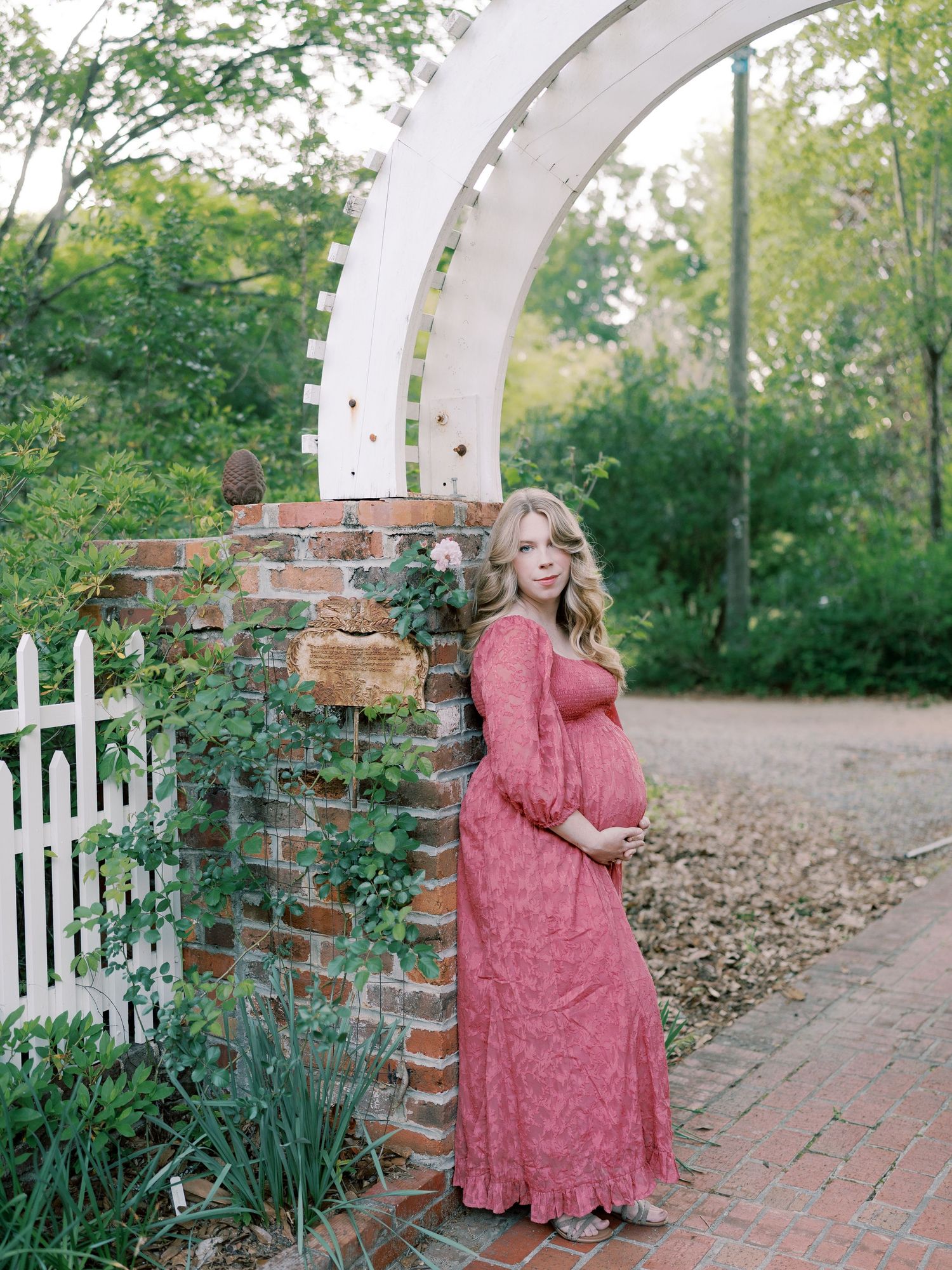 A romantic garden scene with white arched trellis and brick pathways.