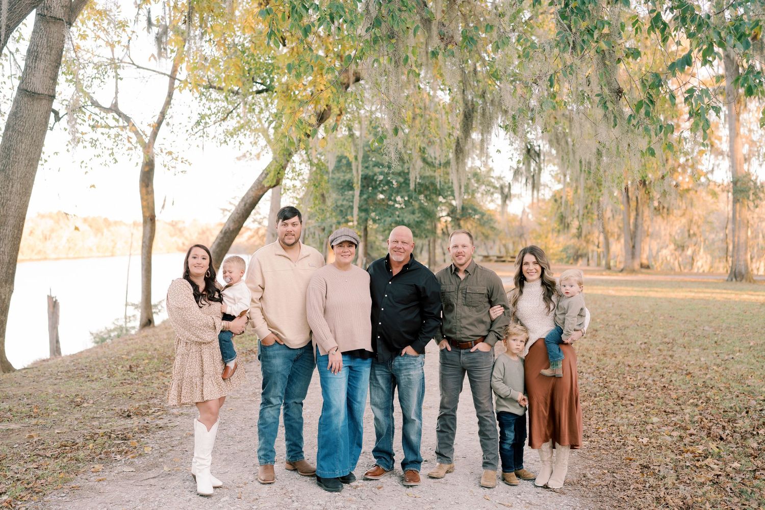 Extended family group photo taken outdoors on a path with fall foliage in the background.