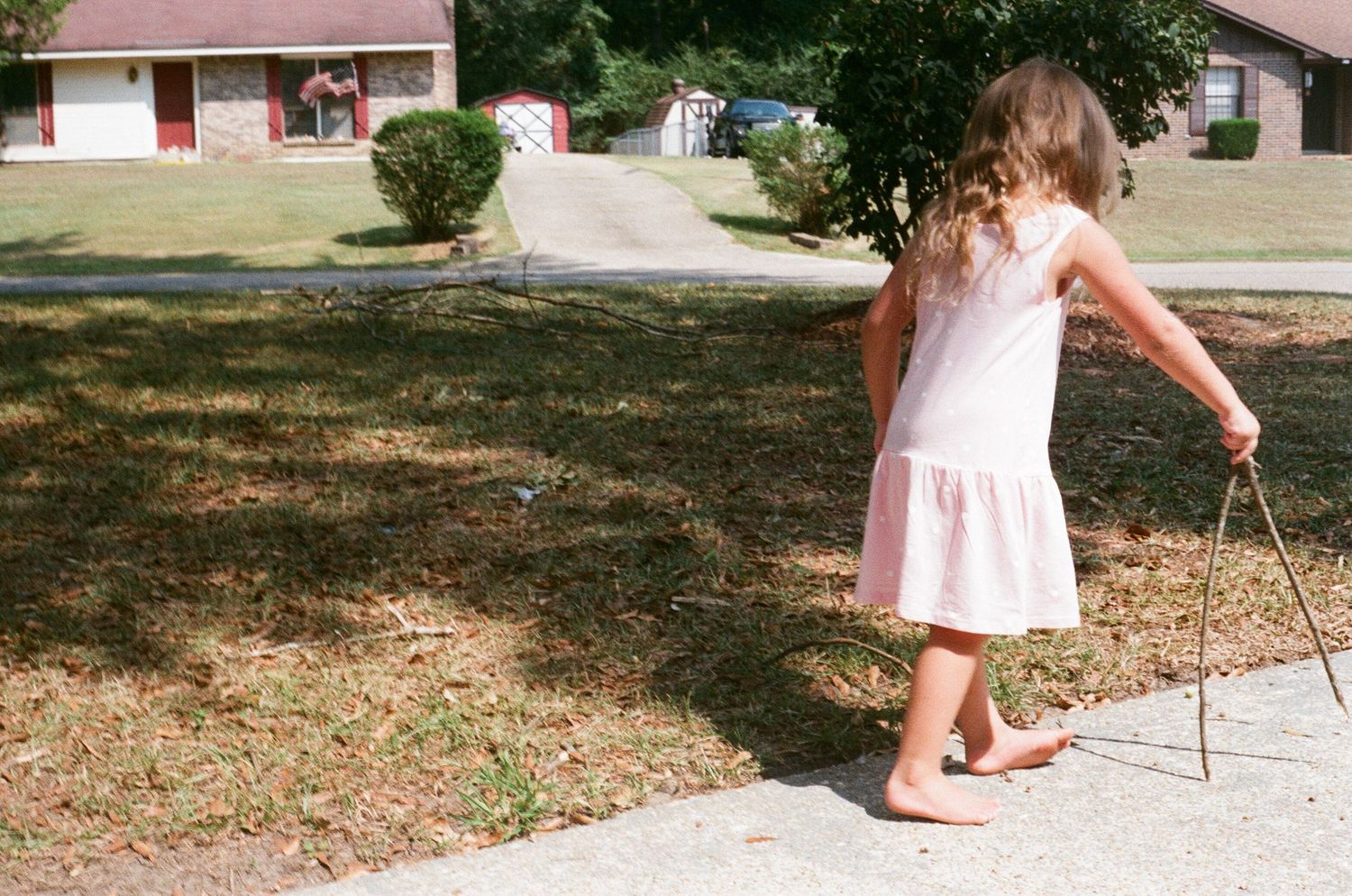 Children in light summer clothing playing in a grassy outdoor area.