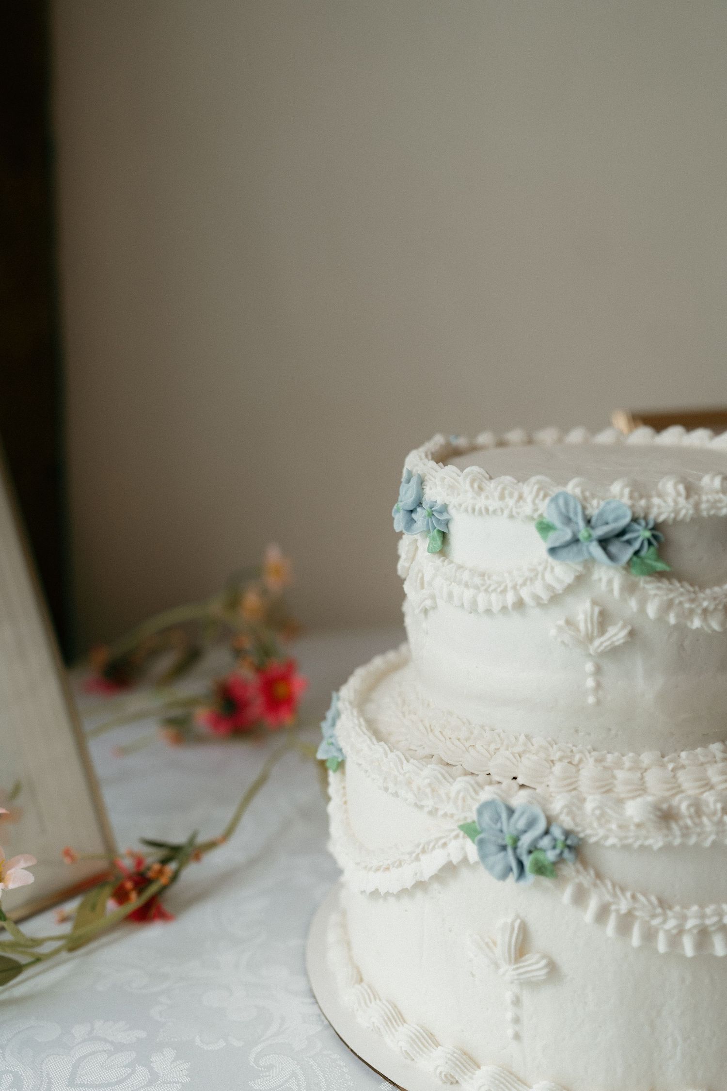 Elegant white wedding cake decorated with delicate lace patterns and pale blue flowers.