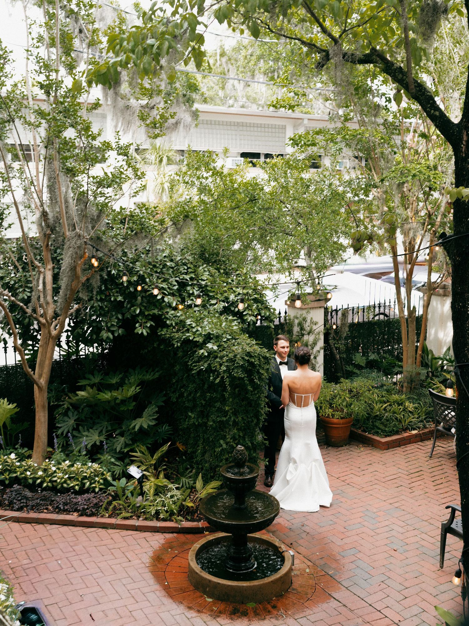 A scenic brick courtyard garden with trees and planters creates an intimate outdoor setting.