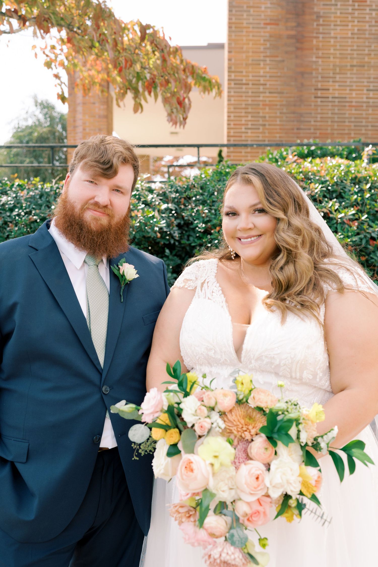 A couple shares joyful moments during their wedding photoshoot with a peach and white floral bouquet.