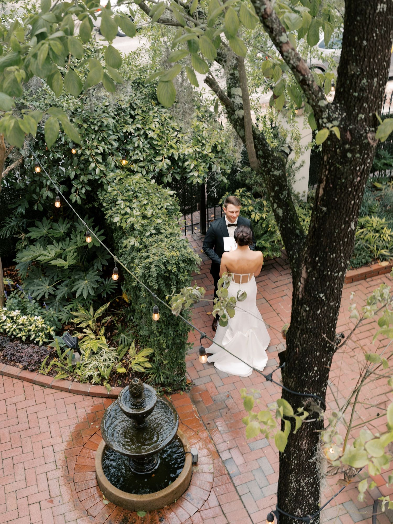 Brick pathway winds through a lush garden with ornamental trees and decorative planters.