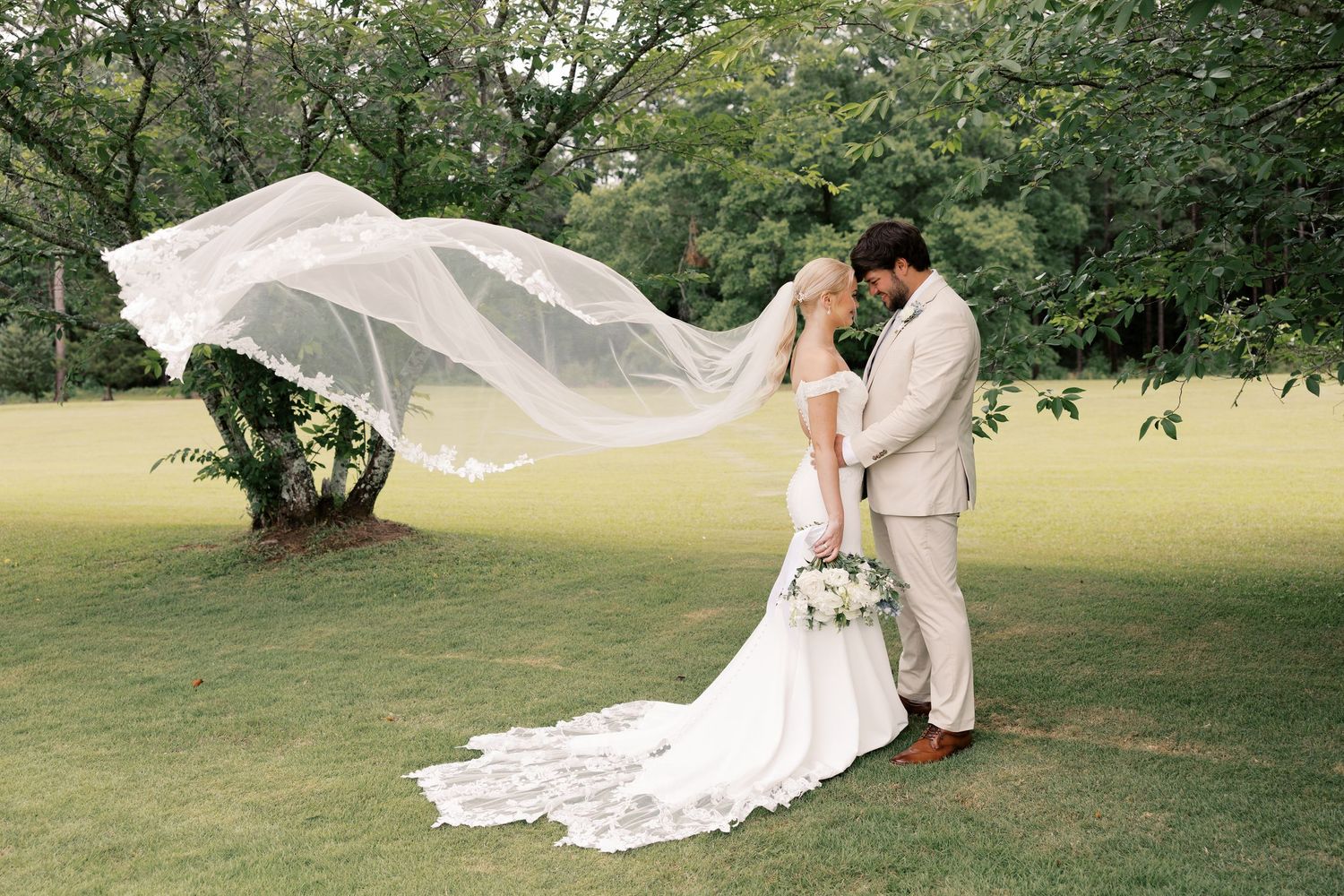 Wedding couple dancing and twirling on green lawn with flowing dress and veil.